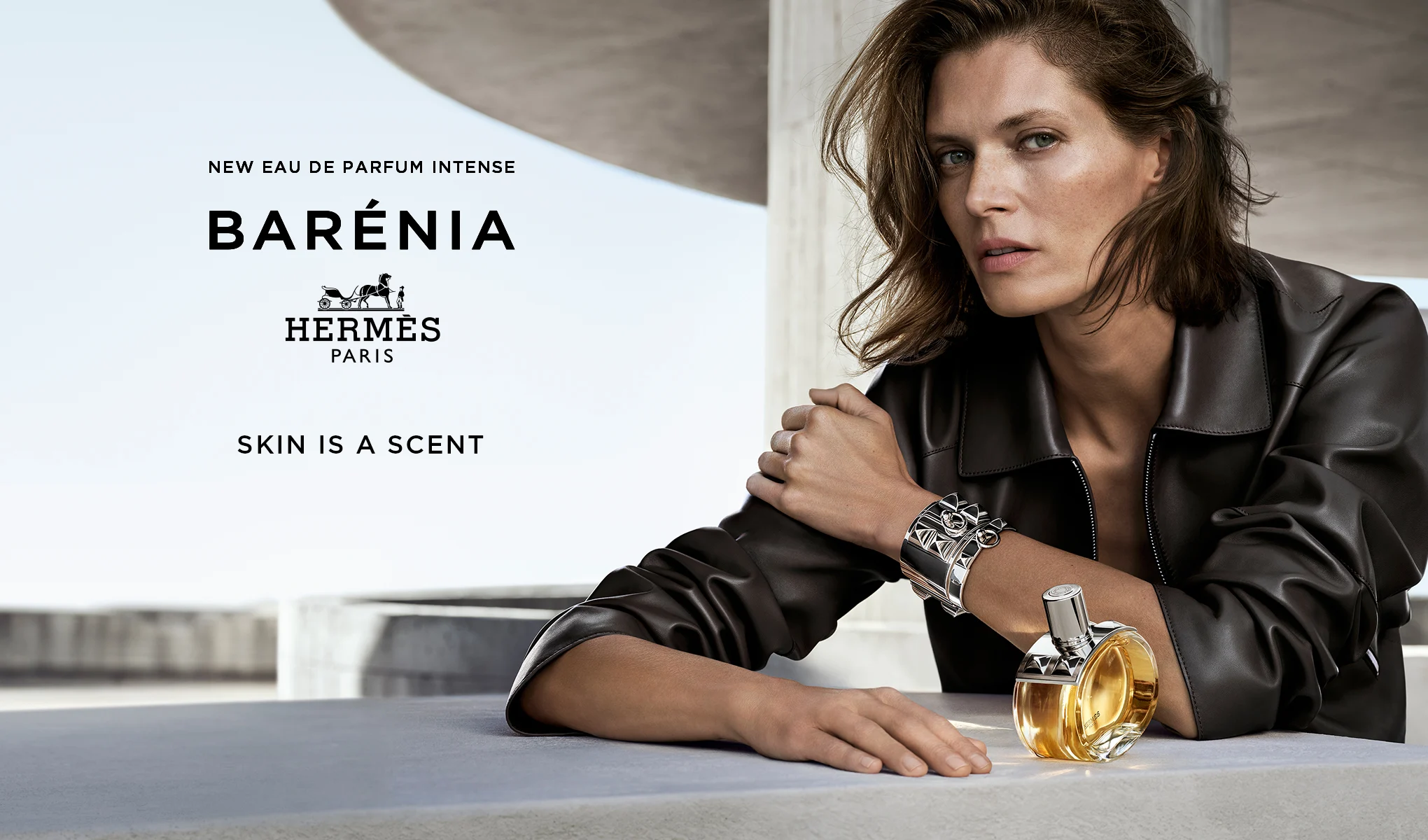 Hermès Barénia Eau de Parfum Intense-flaska, placerad på ett bord bredvid en person i en svart läderjacka.