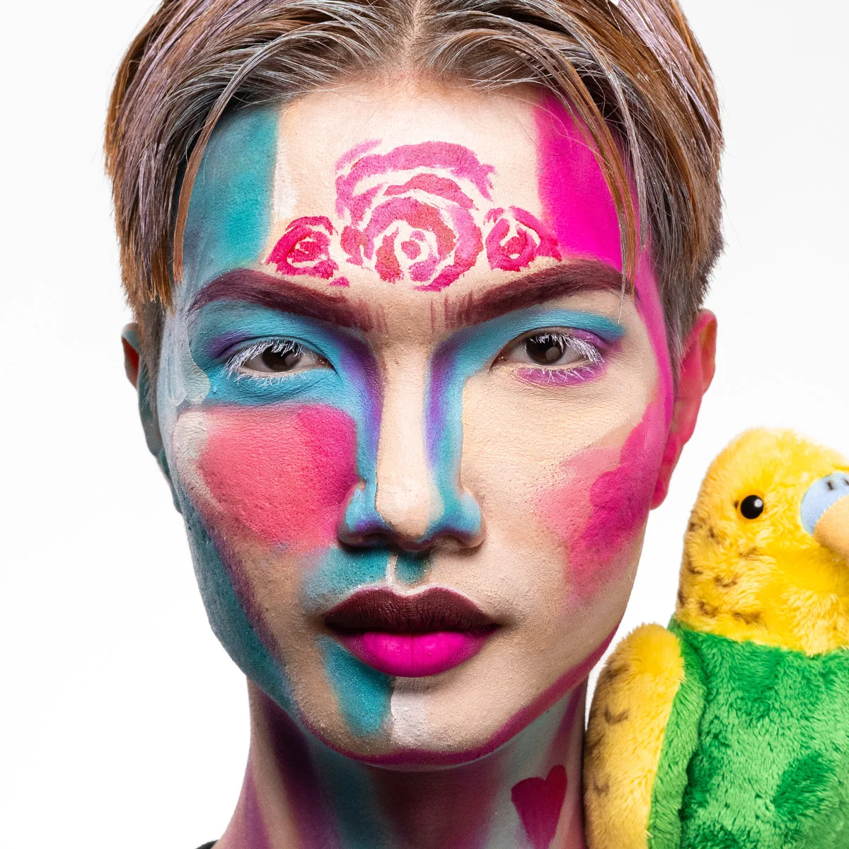 En person med färgglad sminkning och en färgglad mjukisdjurspapegoja på axeln.