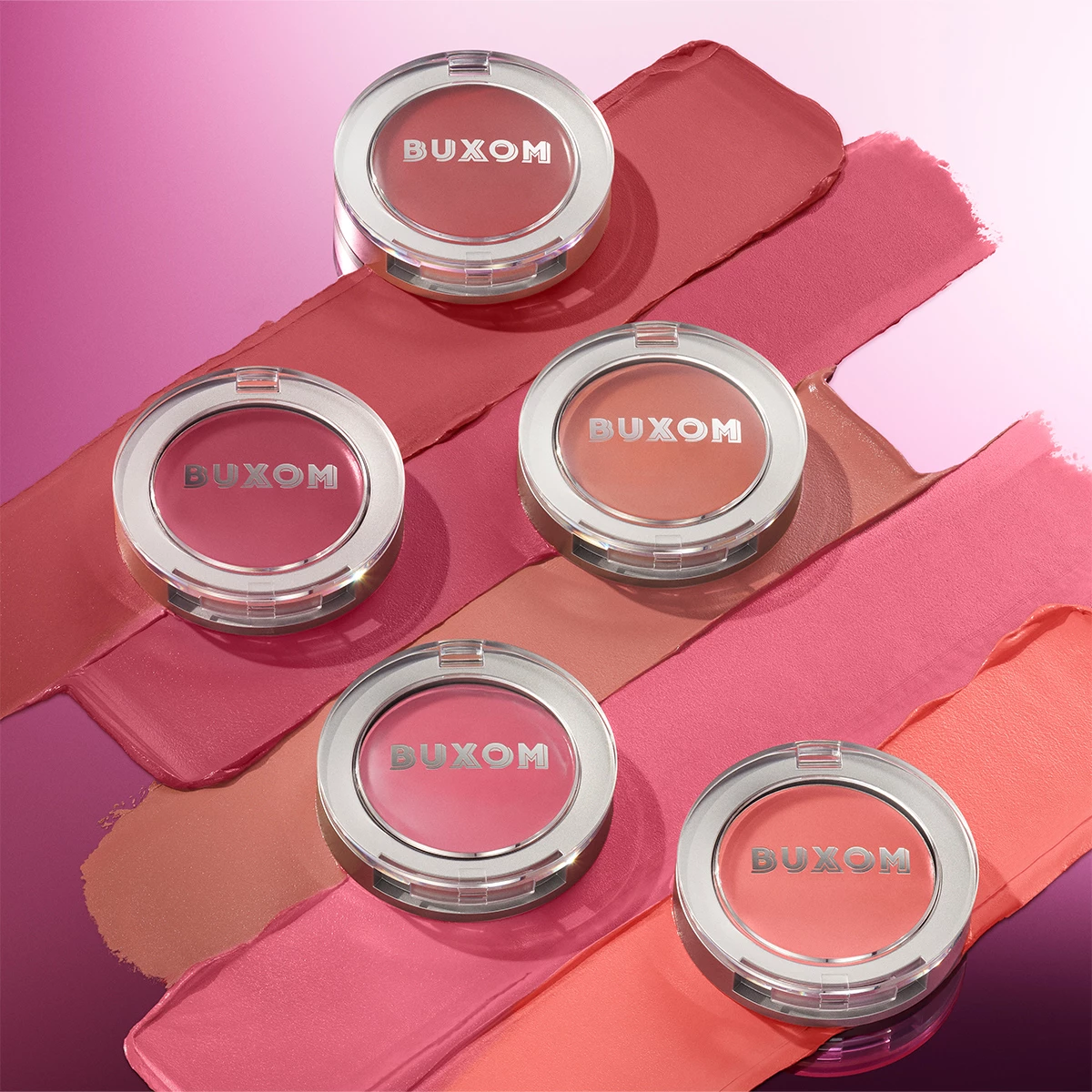  Fem Buxom-blush i forskjellige rosa og korallfarger, arrangert på en bakgrunn med matchende fargestreker.