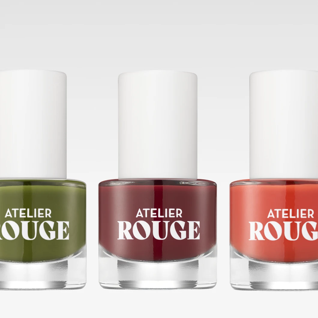 Bild som visar tre nagellacksflaskor från Atelier Rouge. Färgerna på nagellacken är grön, vinröd och orange. Bakgrunden är vit.