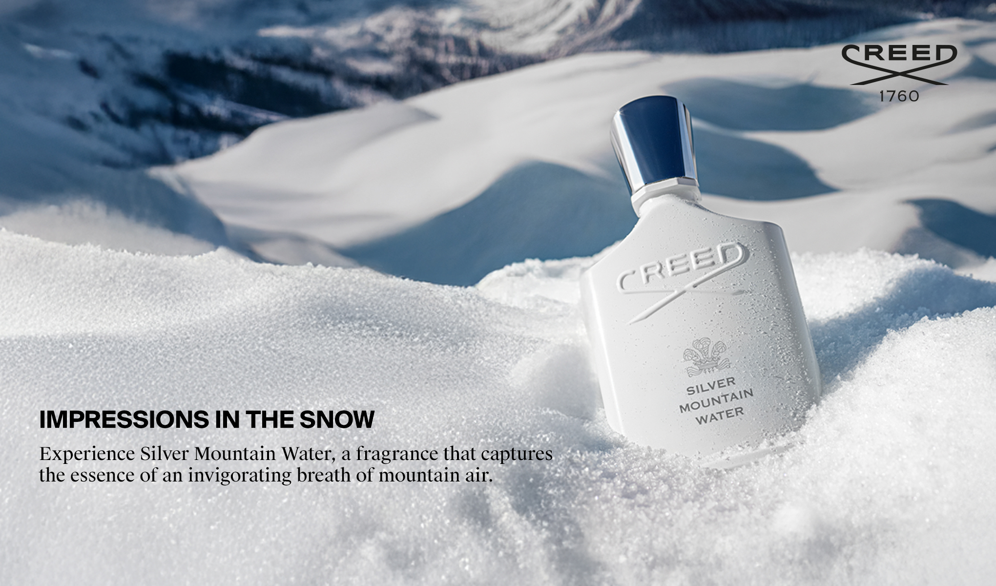 Creed Silver Mountain Water-parfymeflaske plassert i snø i et fjellandskap.