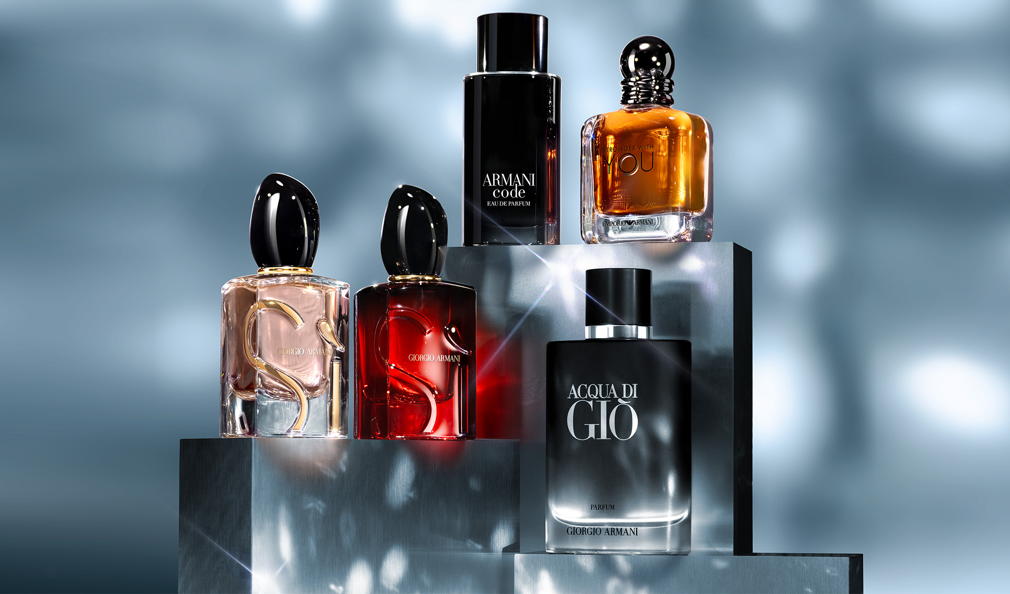 Fem Giorgio Armani-parfymflaskor placerade på en silverfärgad plattform. Bakgrunden har blåaktig, dimmig belysning.