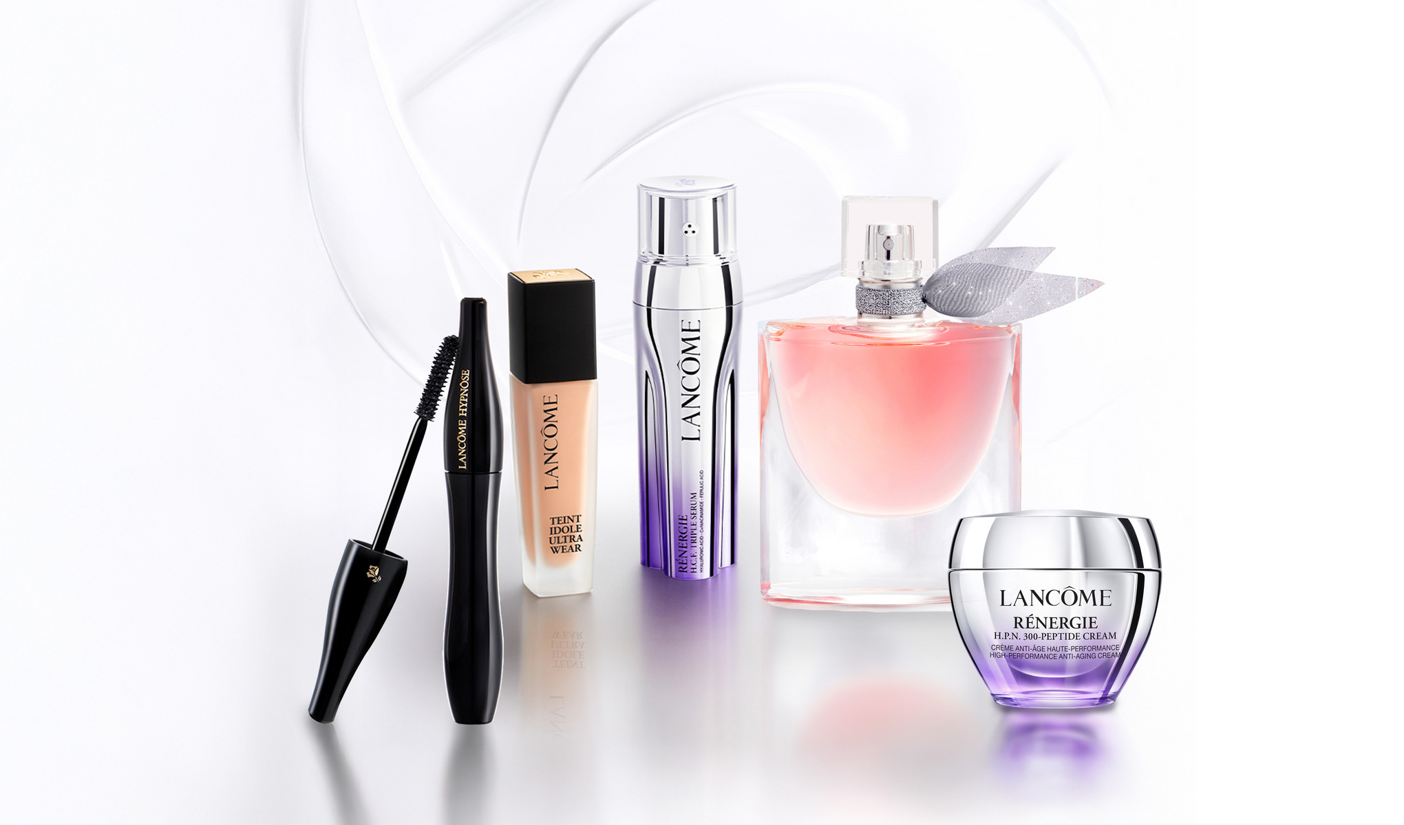 Fem Lancôme-produkter mot ljus bakgrund: mascara med borste, foundation, Rénergie-serum, rosa parfymflaska och Rénergie-ansiktskräm i burk.