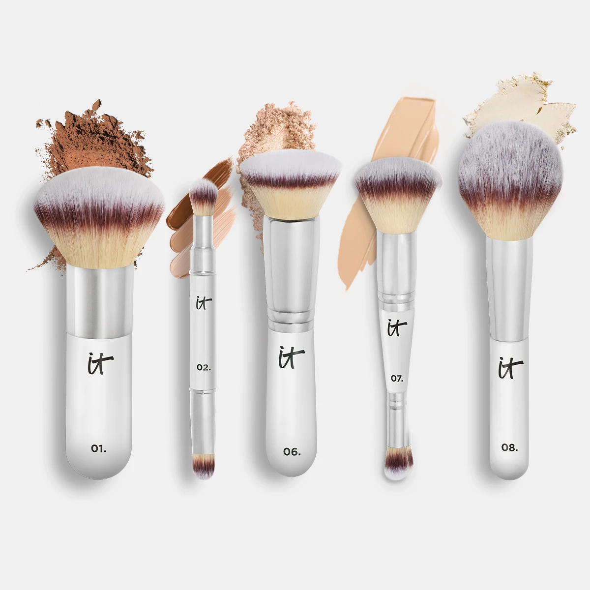 IT Cosmetics -meikkisiveltimiä vaalealla taustalla eri meikkituotteiden tekstuurien kanssa.