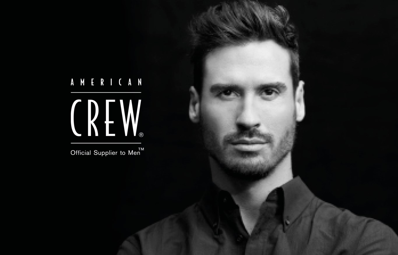 Man med kort, stylat hår och en mörk skjorta. Till vänster om mannen finns texten "American Crew Official Supplier to Men".