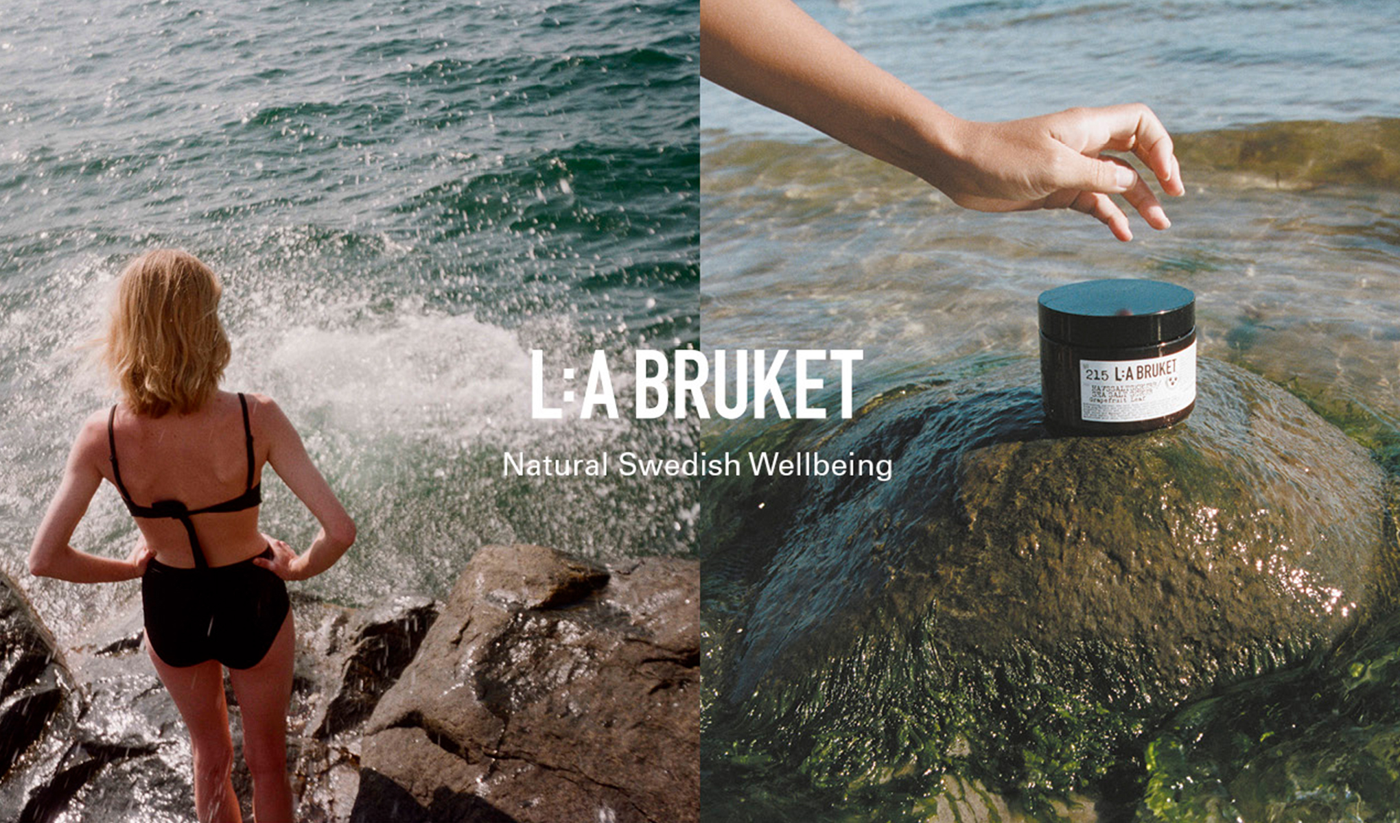 n person står på klippor vid havet med vågor som slår, bredvid syns en hand som sträcker sig mot en L:A Bruket hudvårdsburk på en sten i vattnet.