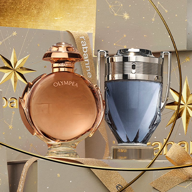 Två guldfärgade sprayflaskor står mot en bakgrund med guldtoner. En stjärna och cirkulära linjer omger flaskorna.