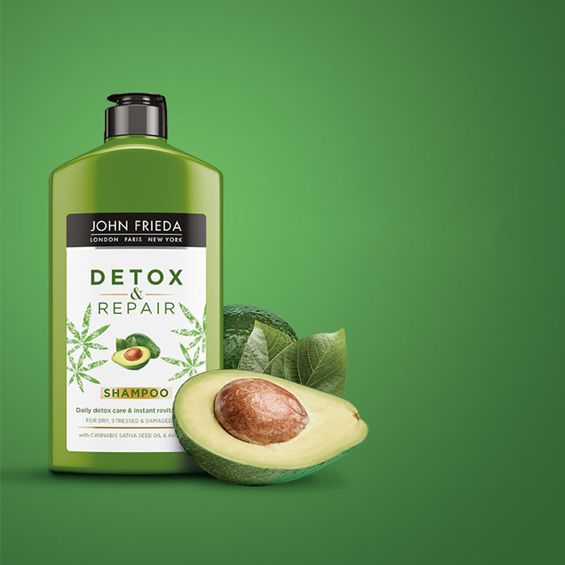Vihreä pullo John Frieda Detox & Repair -shampoota, taustalla avokadoa ja vihreitä lehtiä.
