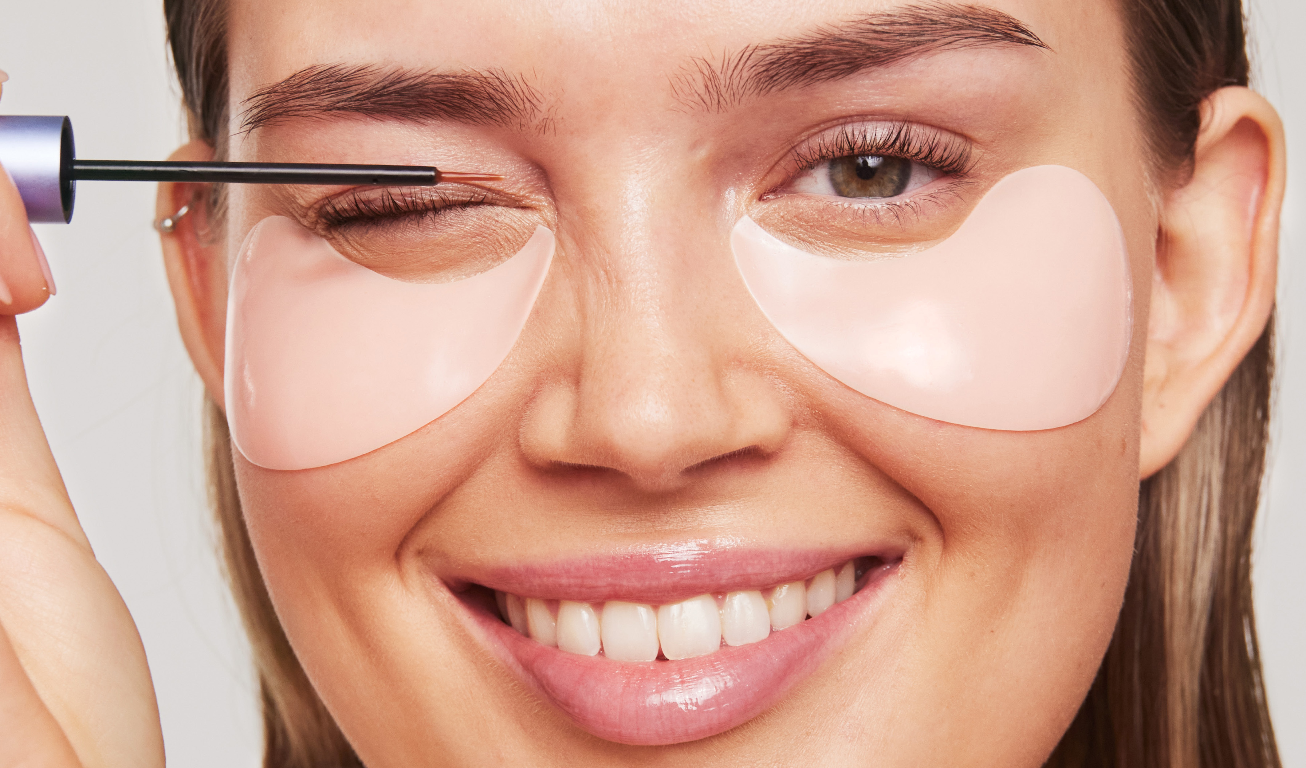 Nainen, jolla on eye patches, levittää ripsiseerumia.