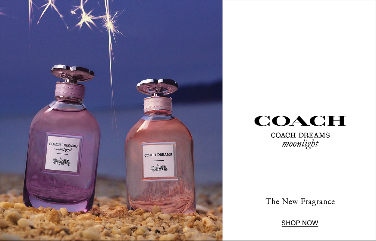 Två parfymflaskor från Coach, med namnet "Coach Dreams Moonlight". Flaskorna är placerade på en strand med småsten, mot en bakgrund av en kvällshimmel med fyrverkerier. Texten "Coach Coach Dreams Moonlight The New Fragrance Shop Now" syns till höger om flaskorna. Flaskorna är i nyanser av rosa och lila.