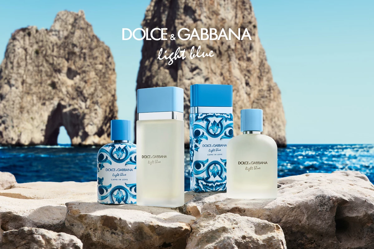Dolce & Gabbana Light Blue parfymflaskor står på klippor, med blått hav och bergformation i bakgrunden.
