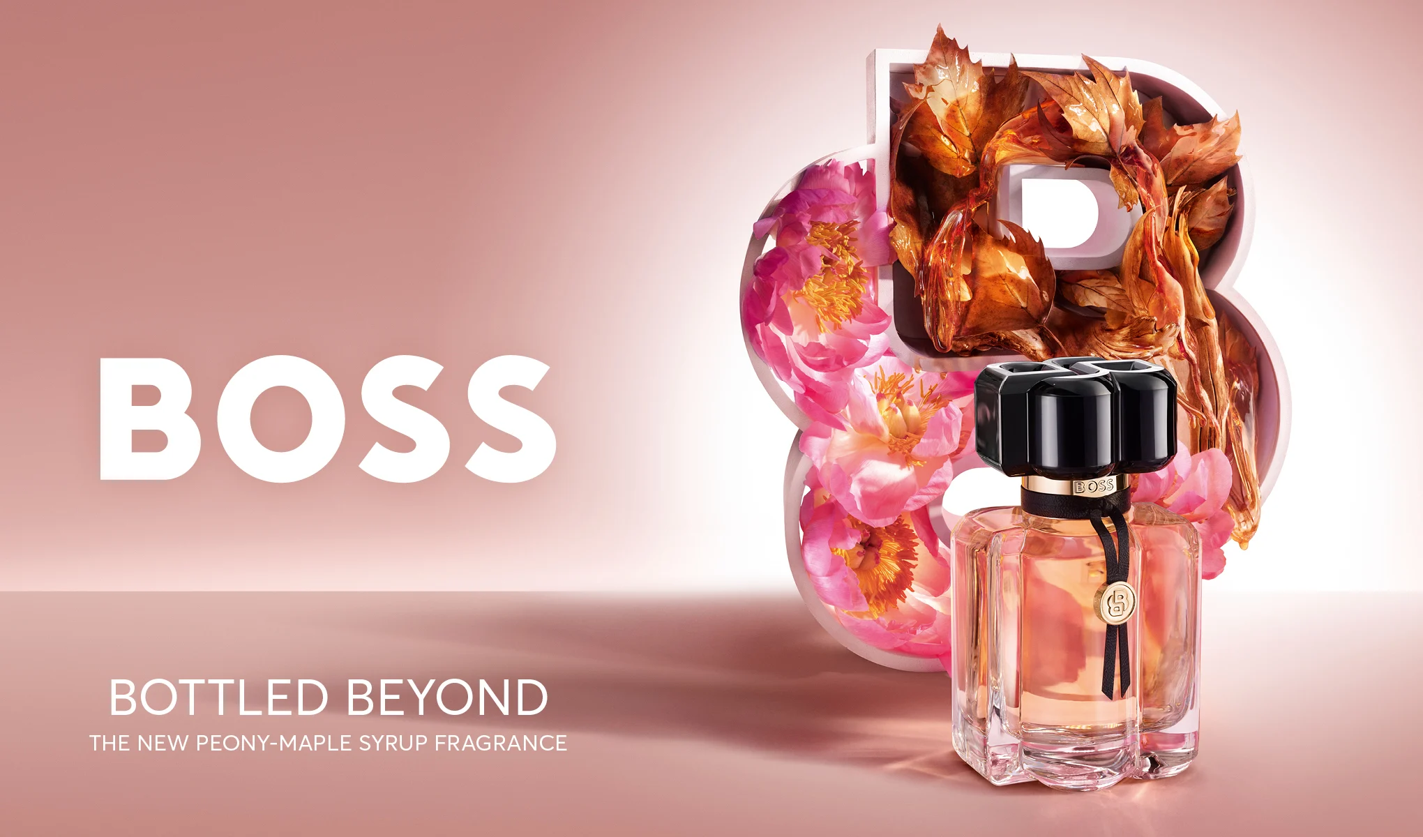 BOSS Bottled Beyond Eau de Parfum i en gjennomsiktig glassflaske med svart kork står foran en stor B fylt med peoner og høstblader mot en rosa bakgrunn. Synlig tekst: "BOSS", "BOTTLED BEYOND" og "THE NEW PEONY-MAPLE SYRUP FRAGRANCE".