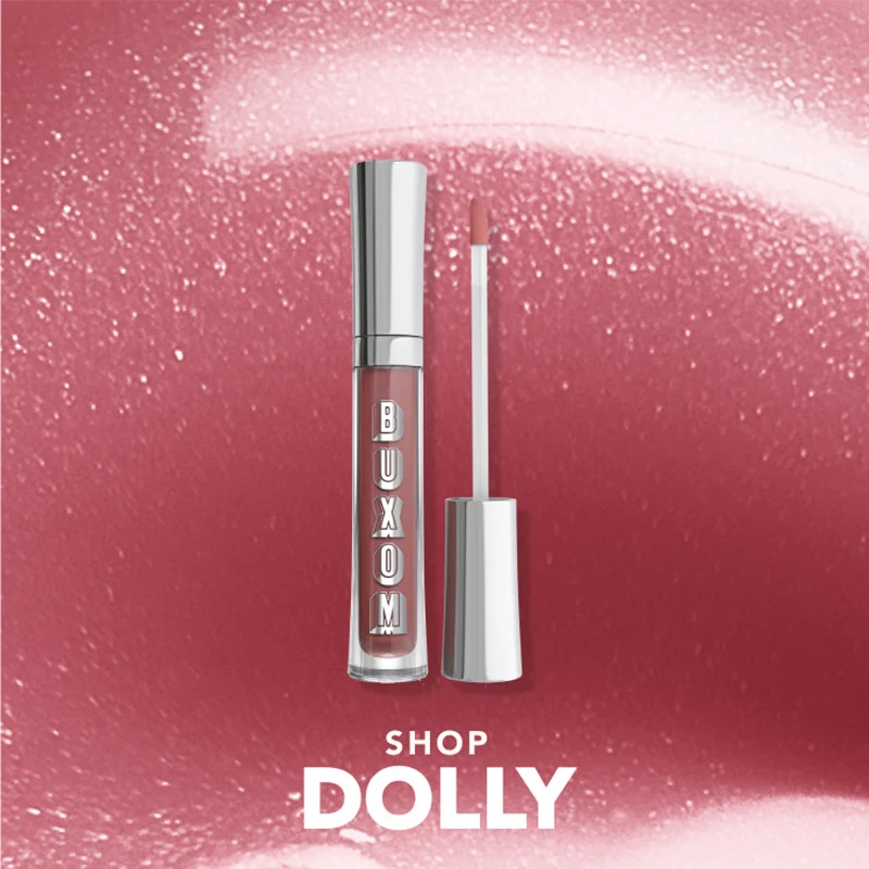 Buxom lipgloss i en gjennomsiktig tube med sølvhette og applikator som viser en nude-rosa fargetone. Tekst: Shop Dolly.