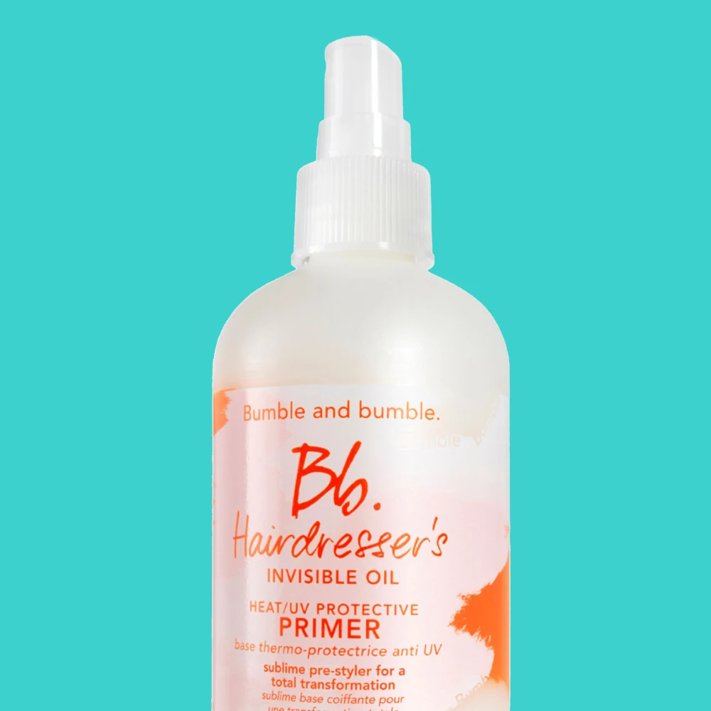 Bumble and bumble Hairdresser's Invisible Oil Heat/UV Protective Primer. Valkoinen suihkepullo oransseilla yksityiskohdilla turkoosilla taustalla.