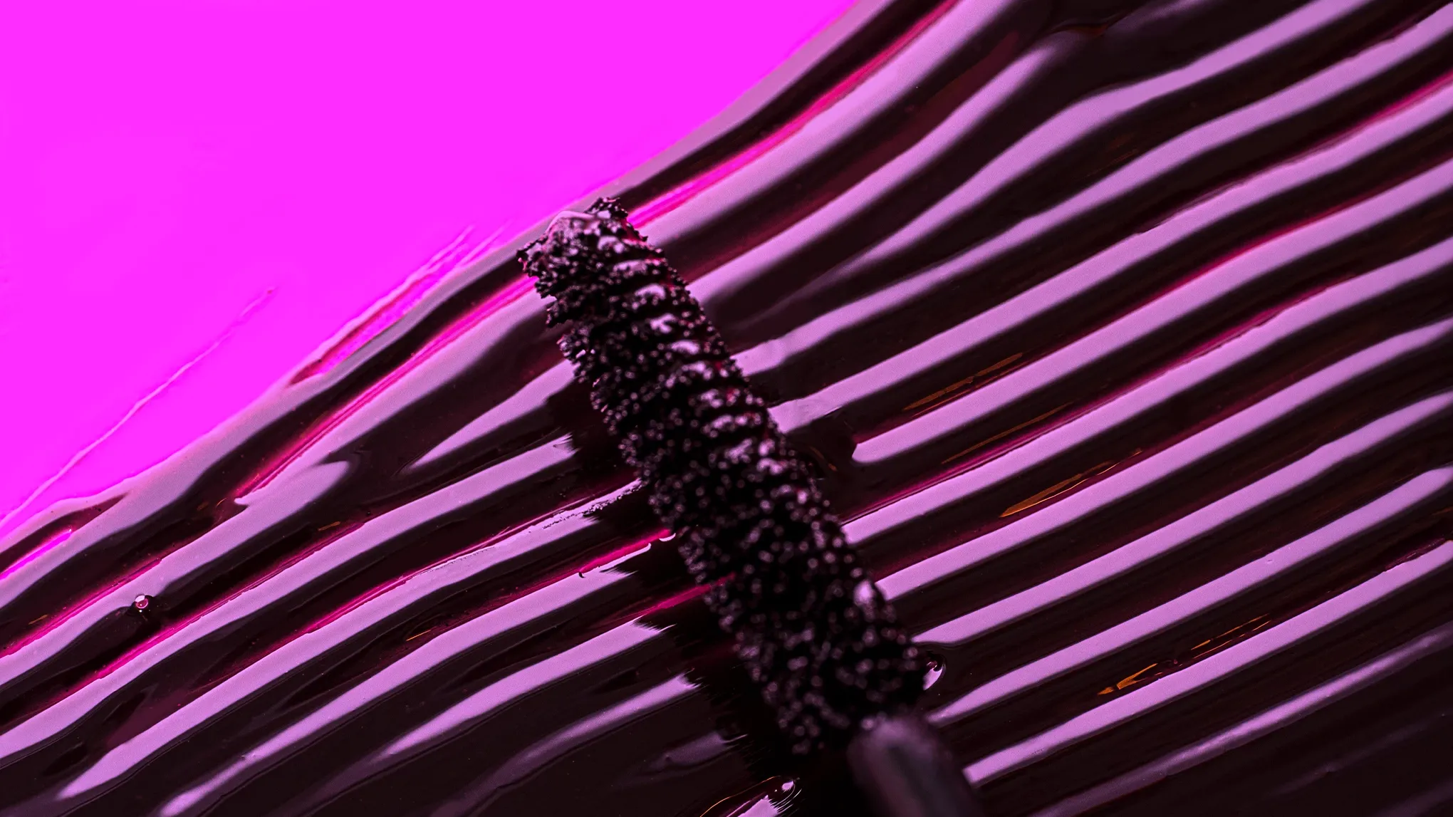 Mascara genomstruken med en mascaraborste i lila ljus