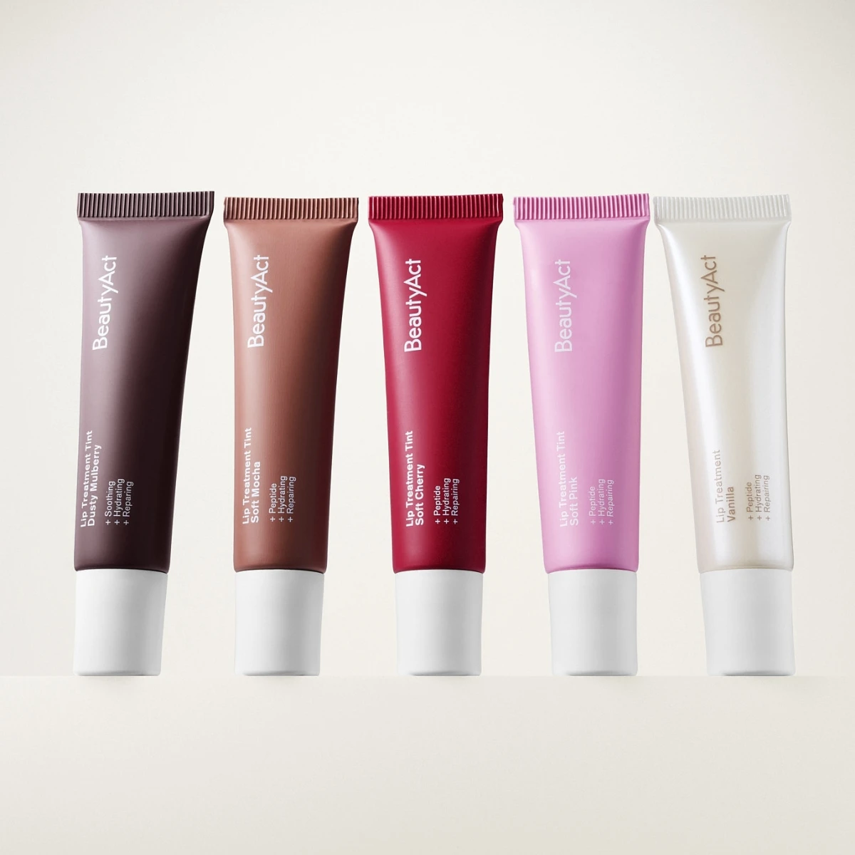Fem BeautyAct läpprodukter i tub med olika nyanser som brun, nude, röd, rosa och transparent, med synlig text “BeautyAct”, “Lip Treatment Tint” och “SPF 15” på ljus bakgrund.