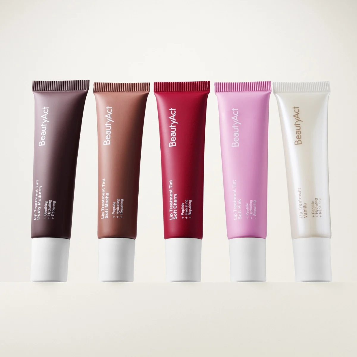 Fem BeautyAct läpprodukter i tub med olika nyanser som brun, nude, röd, rosa och transparent, med synlig text “BeautyAct”, “Lip Treatment Tint” och “SPF 15” på ljus bakgrund.