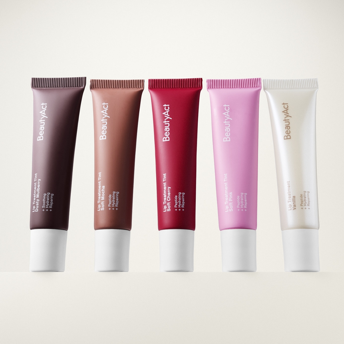 Fem BeautyAct leppeprodukter i tube i ulike nyanser som brun, nude, rød, rosa og transparent, med synlig tekst “BeautyAct”, “Lip Treatment Tint” og “SPF 15” mot lys bakgrunn.