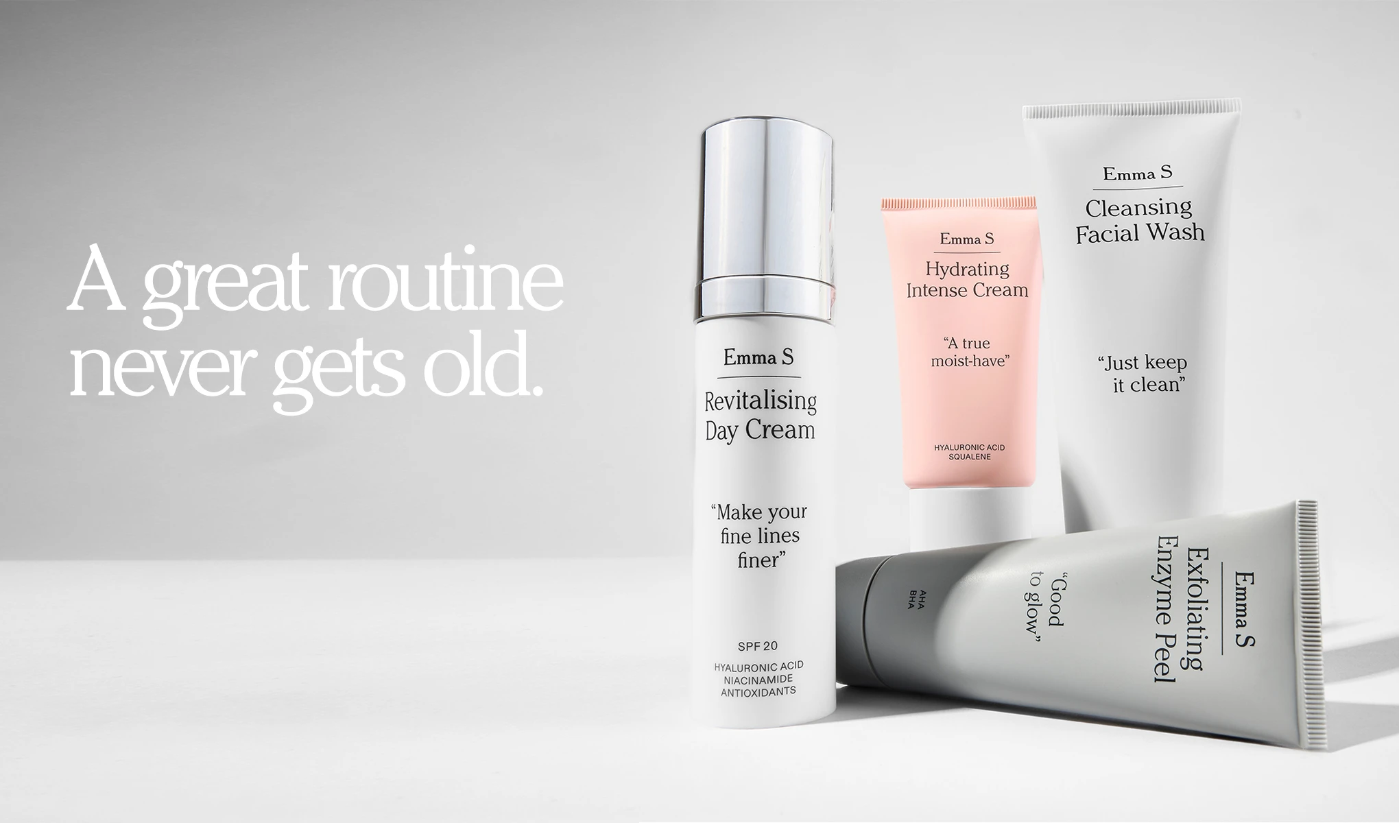 Emma S -ihonhoitotuotteet vaalealla taustalla: Revitalising Day Cream SPF 20 tekstillä “Make your fine lines finer”, Hydrating Intense Cream “A true moist-have”, Cleansing Facial Wash “Just keep it clean” ja Exfoliating Enzyme Peel “Good to glow”. Vasemmalla näkyy teksti “A great routine never gets old.” sekä pakkauksissa ainesosatekstit Hyaluronic Acid, Niacinamide, Antioxidants, AHA, BHA ja Squalene.