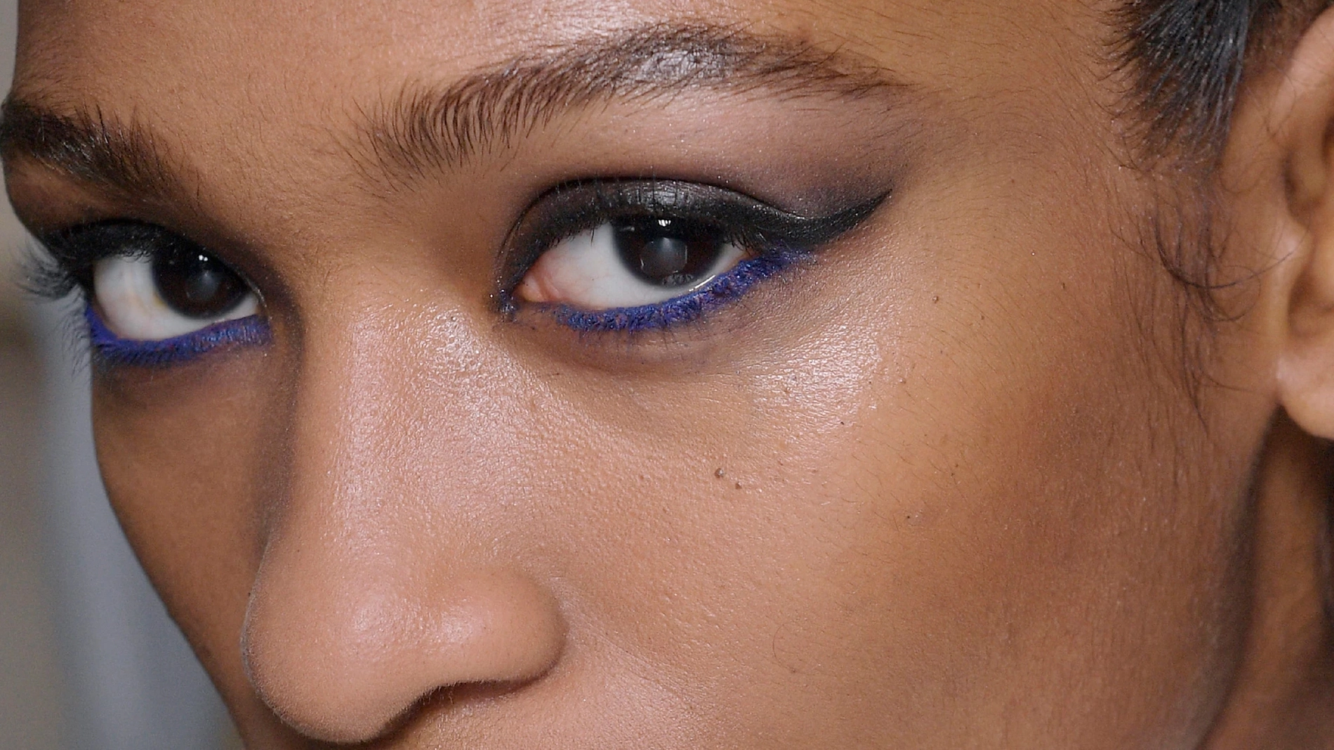 Närbild på en kvinnas ögon, sminkade med svart och blå eyeliner