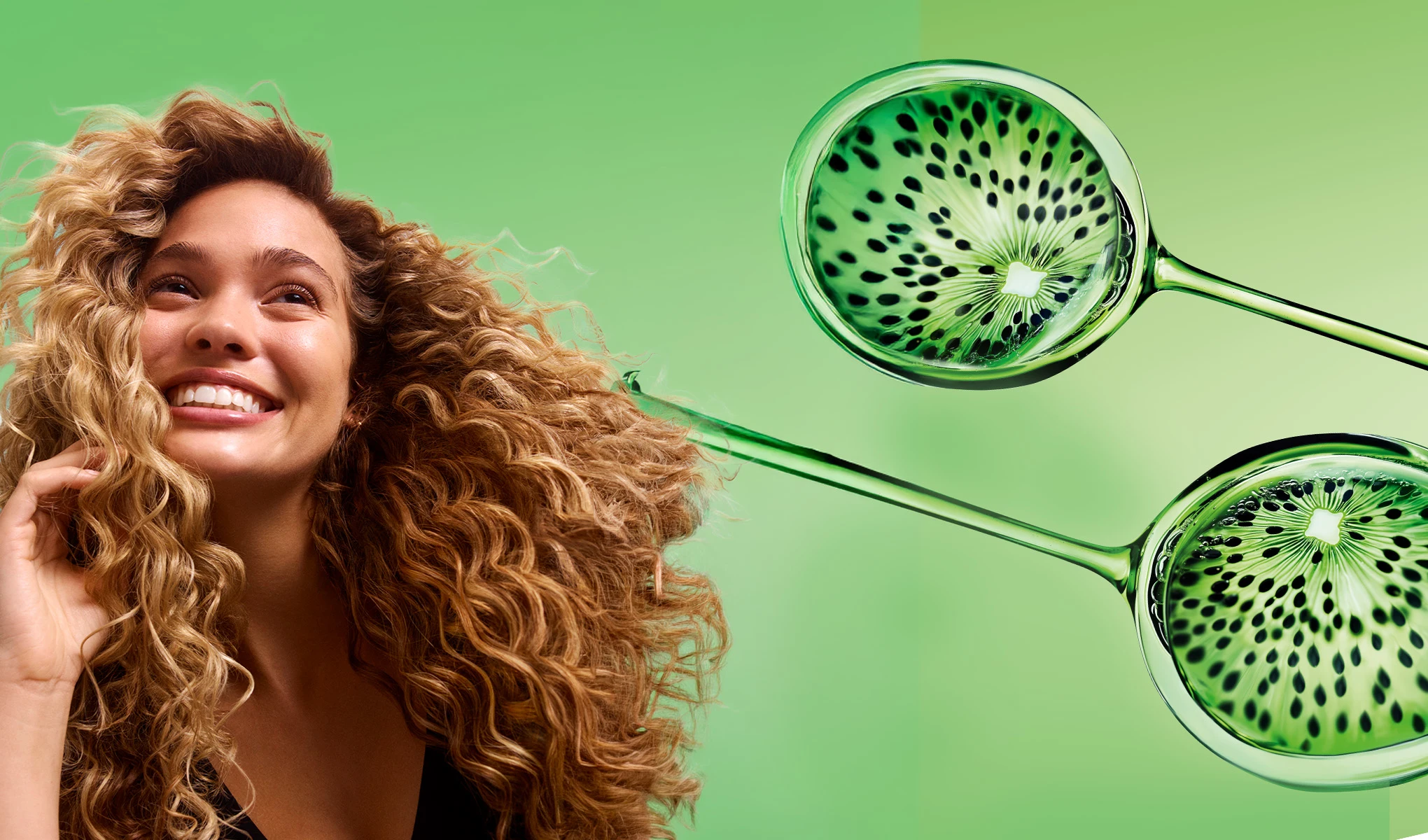 Kvinna med lockigt hår och ett leende. Två pipetter med kiwi, en droppar i håret. Grön bakgrund.