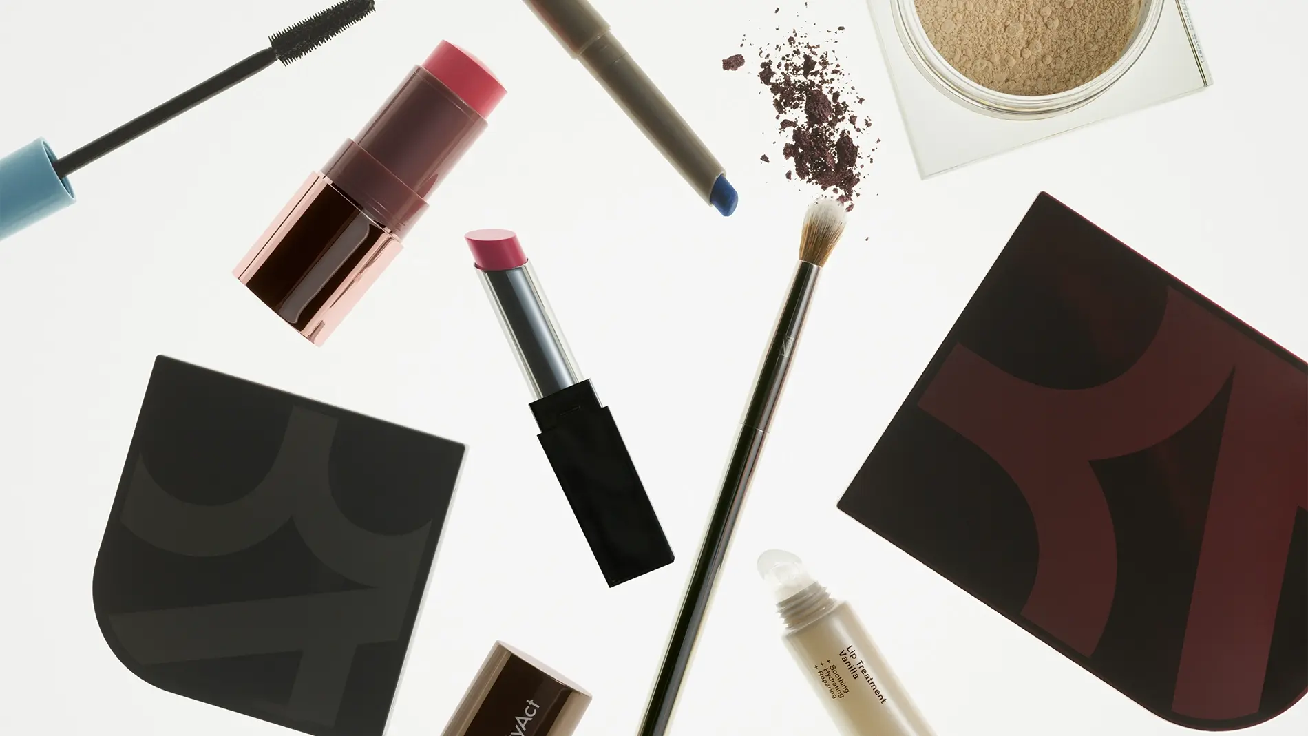 Sminkprodukter visas mot vit bakgrund, inklusive mascara, läppstift, ögonskugga, puder, läppenna, läppbehandling och sminkborste tillsammans med makeup-paletter. Bilden innehåller produkter för makeup och skönhet med synliga detaljer som blå eyeliner, rosa läpprodukter och löst puder.