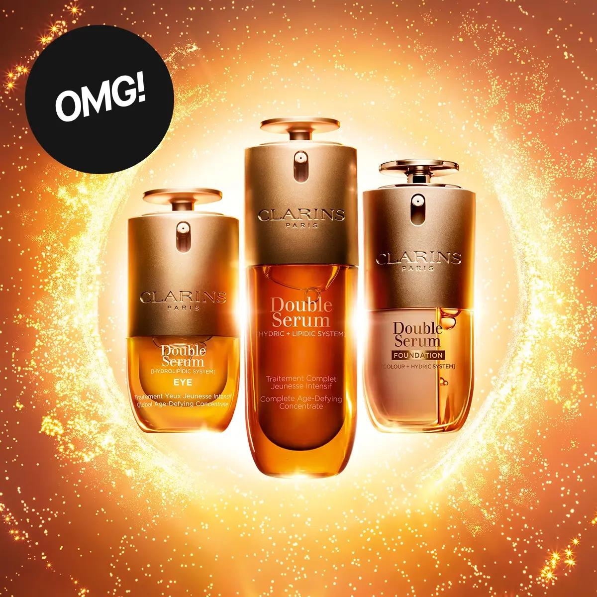 OMG! Clarins Paris Double Serum Eye, Double Serum og Double Serum Foundation vises i gylne forpakninger mot en glitrende gull- og oransjefarget bakgrunn.