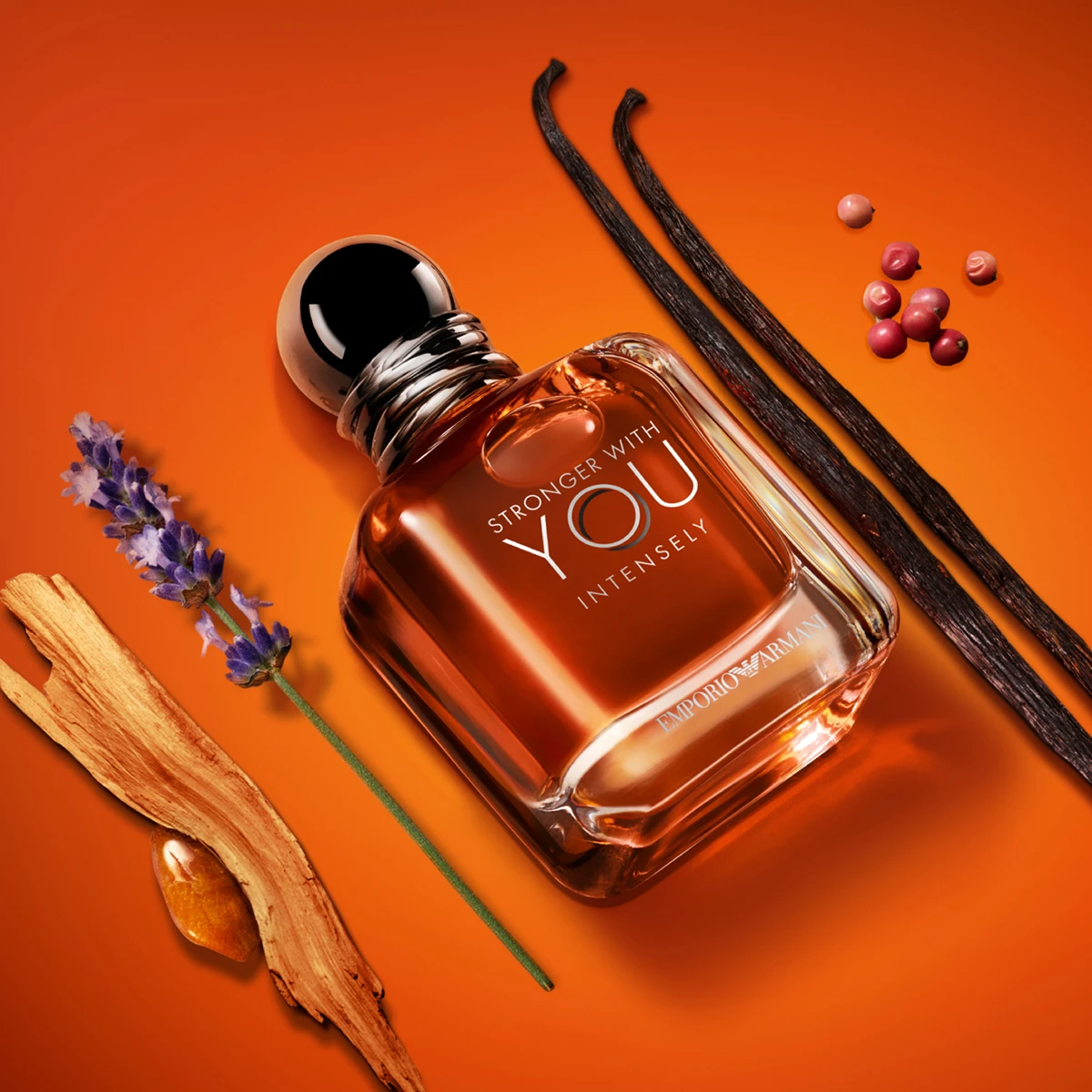 Emporio Armani Stronger With You Intensely -parfyymipullo oranssilla taustalla, vaniljatankoja, laventelia ja mausteisia yksityiskohtia.