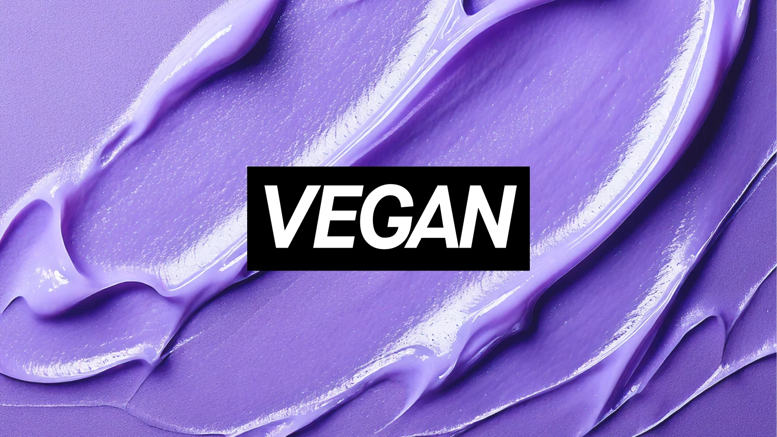 Violetti tausta, jossa on kiiltävä ja voidemainen kosmetiikkatuotteen koostumus sekä teksti ”VEGAN”.