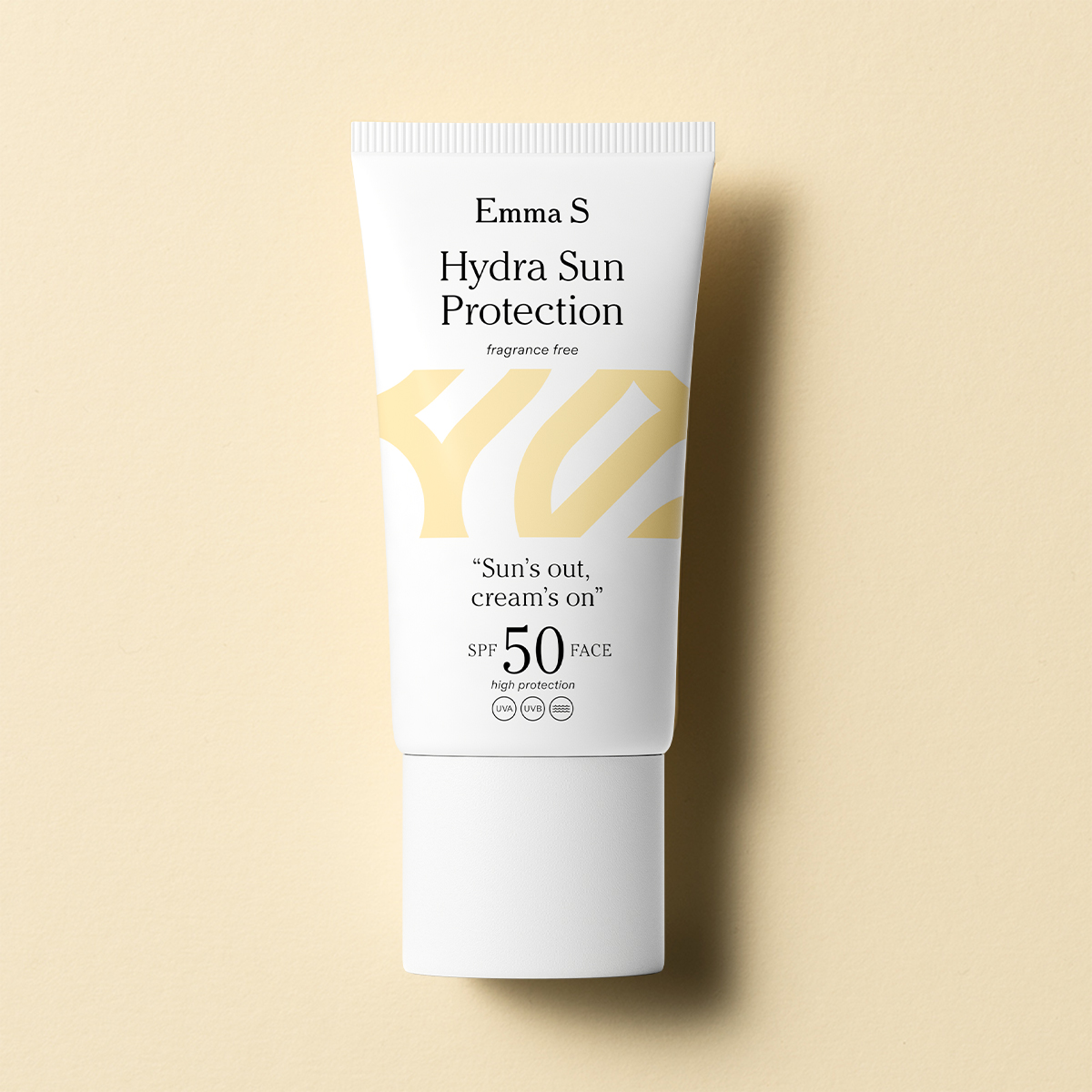 En gul tub med Emma S. Hydra Sun Protection  SPF 50, med texten "Sun's out, cream's on" på framsidan, placerad mot en ljusgul bakgrund.