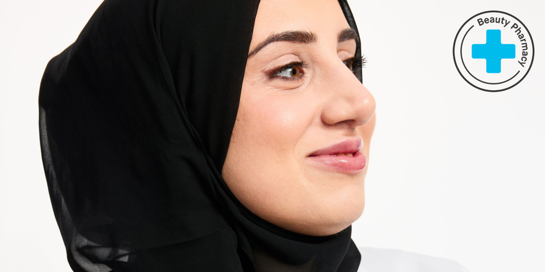 En person klädd i en vit läkarrock med ett blått kors på bröstet och en svart hijab.