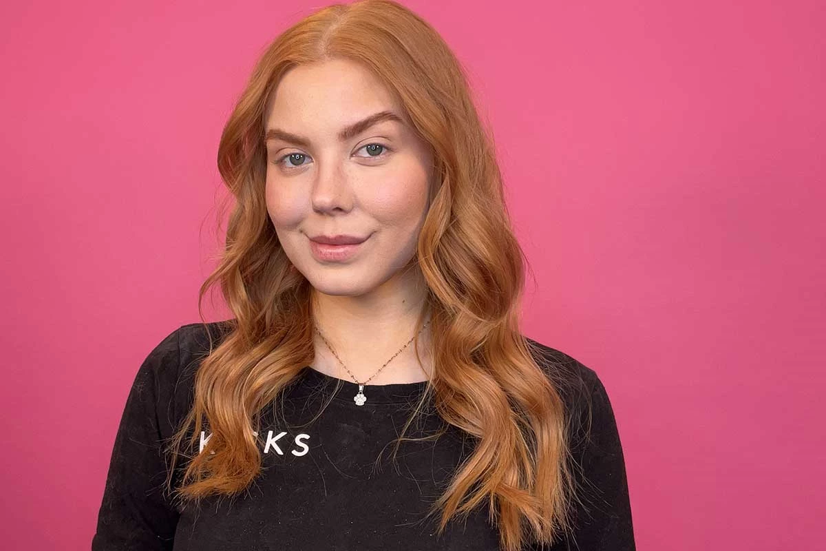 KICKS-kauneusasiantuntija Isabella kihartaa hiuksensa kirnaista taustaa vasten.