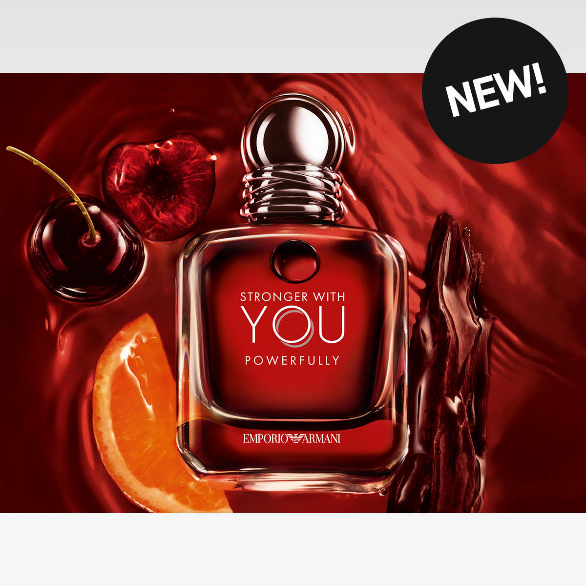 Emporio Armani Stronger With You Powerfully parfymflaska mot röd bakgrund med körsbär och citrus.