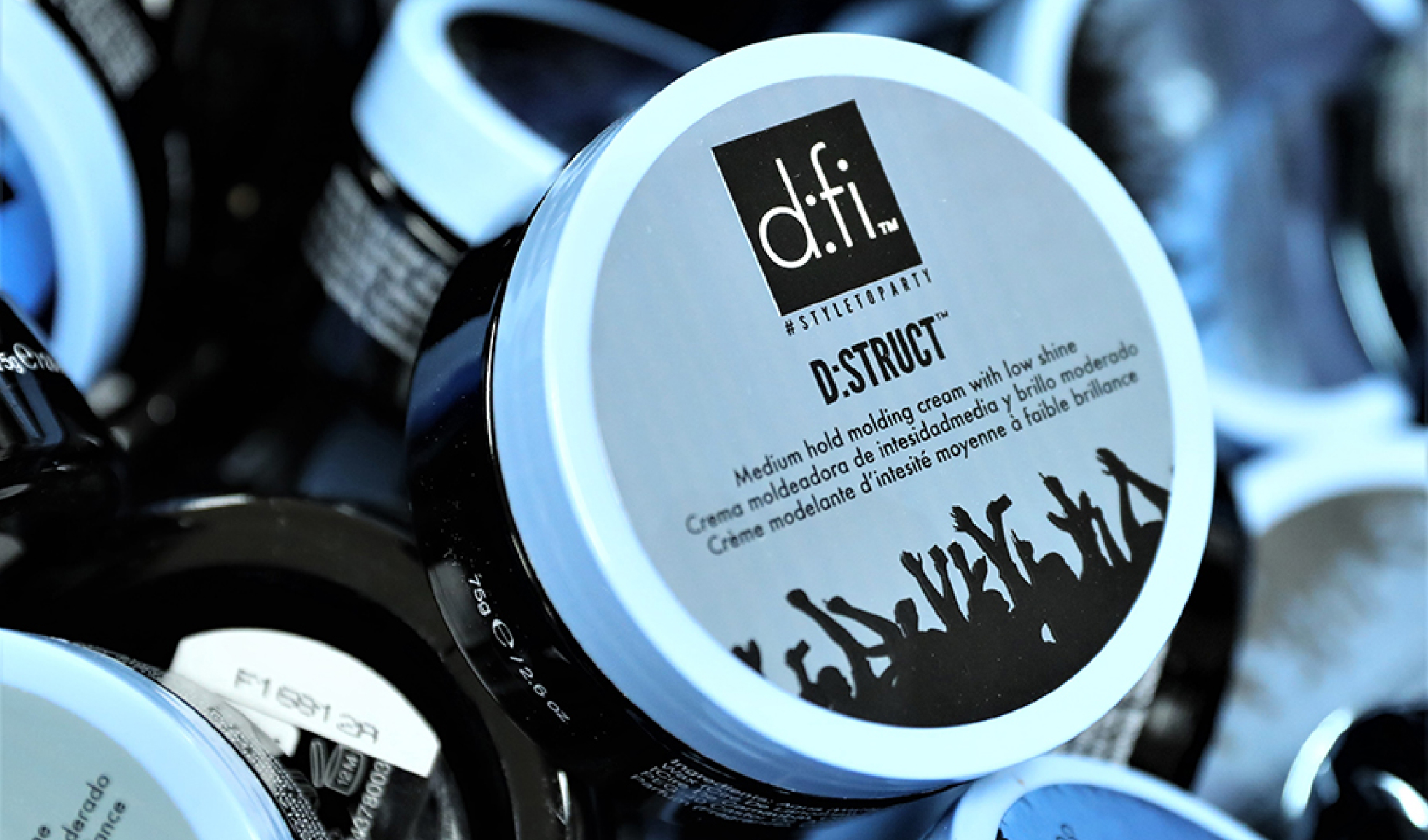 D-Struct stylingkräm. Rund burk med ljusblått lock och svart text. I bakgrunden finns flera liknande burkar.
