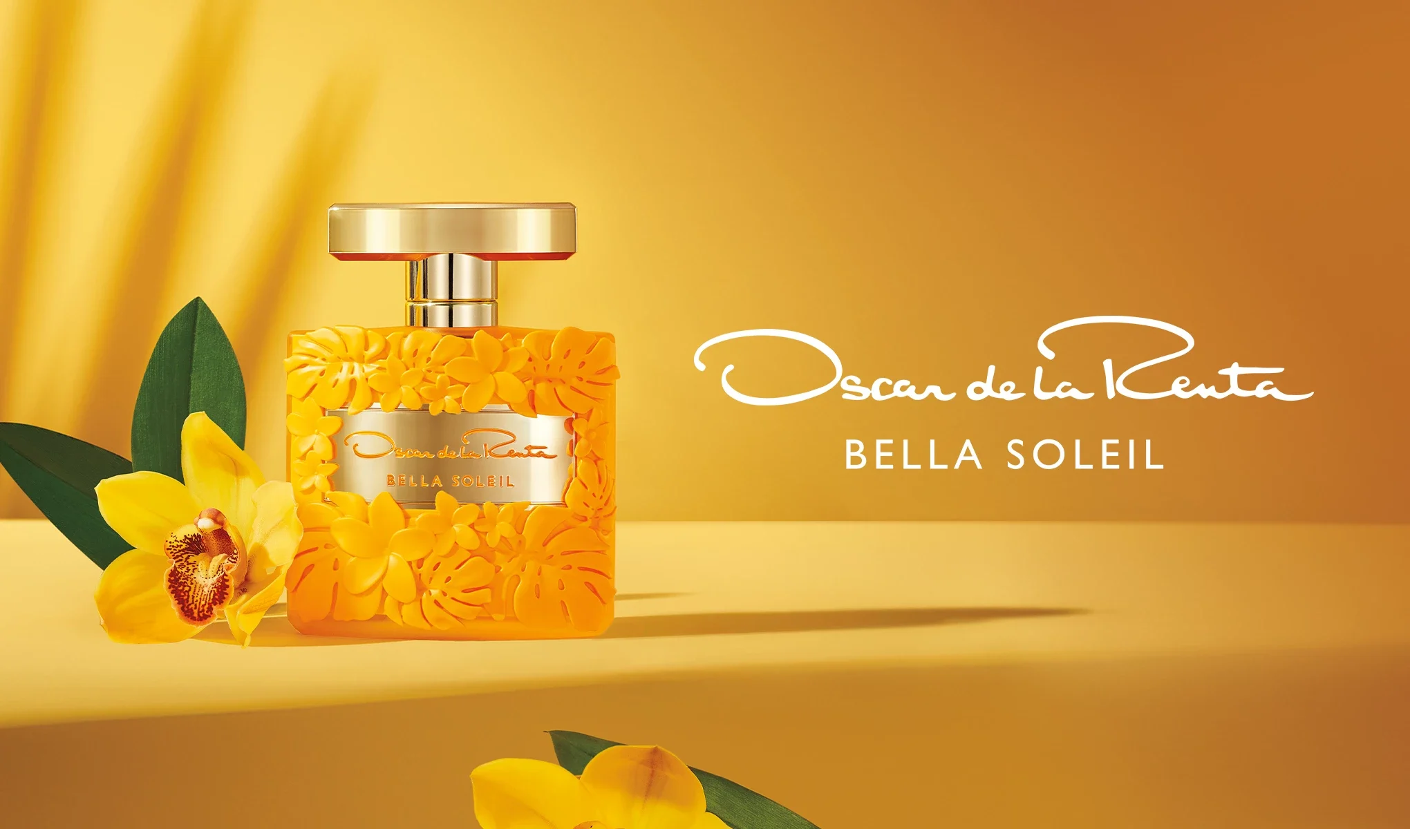 Kuvassa on keltainen Oscar de la Rentan "Bella Soleil" -hajuvesipullo keltaisella taustalla, koristeltuna kukilla. Pullon vieressä on keltainen kukka vihreillä lehdillä.
