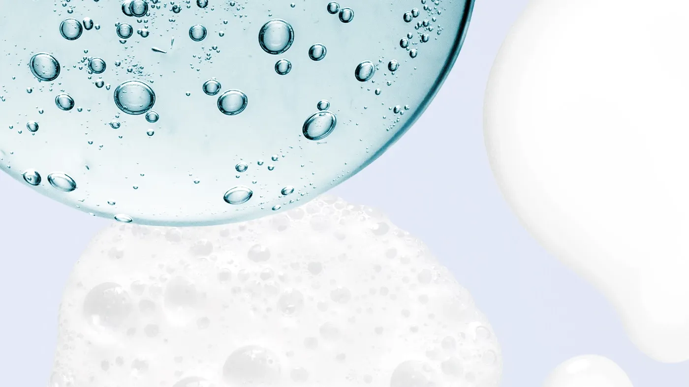 Blå, bubblig vätska intill vitt skum och kräm, mot en blå bakgrund.