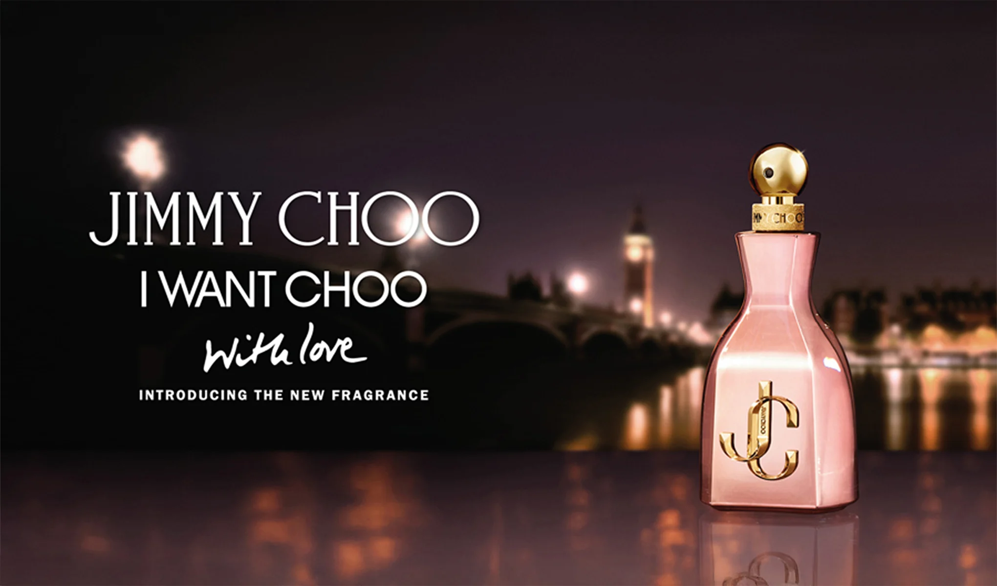 Jimmy Choo-parfymeflasken er plassert foran et glødende nattlandskap. I bakgrunnen vises byens silhuett og lys, som skaper en romantisk atmosfære.