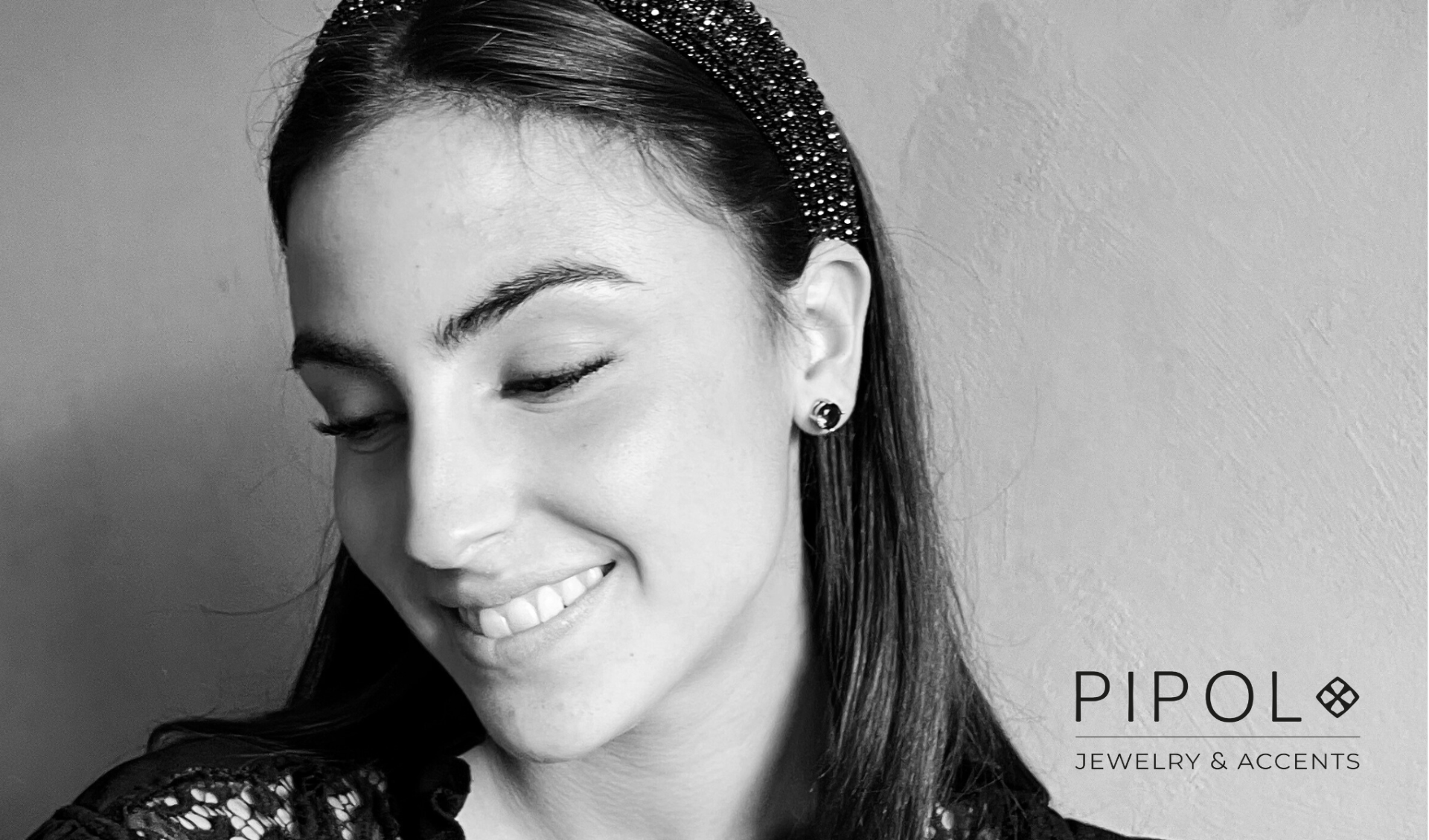Kuva naisesta, jolla on musta hiuspanta ja mustat korvakorut. Kuvan oikeassa alakulmassa teksti "PIPOL Jewelry & Accents".