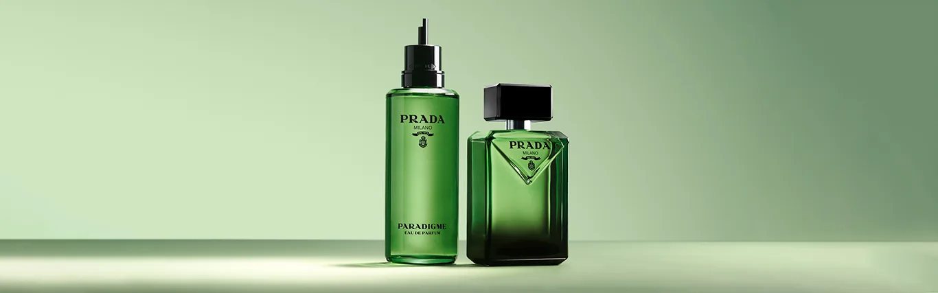 Två gröna Prada Paradigme-parfymflaskor på en ljusgrön bakgrund.