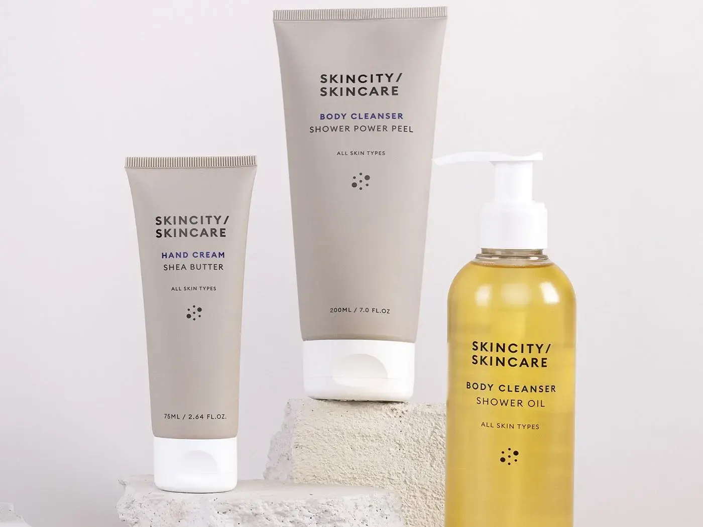 Tre produkter fra Skincity Skincare plassert på steiner, mot en grå bakgrunn.