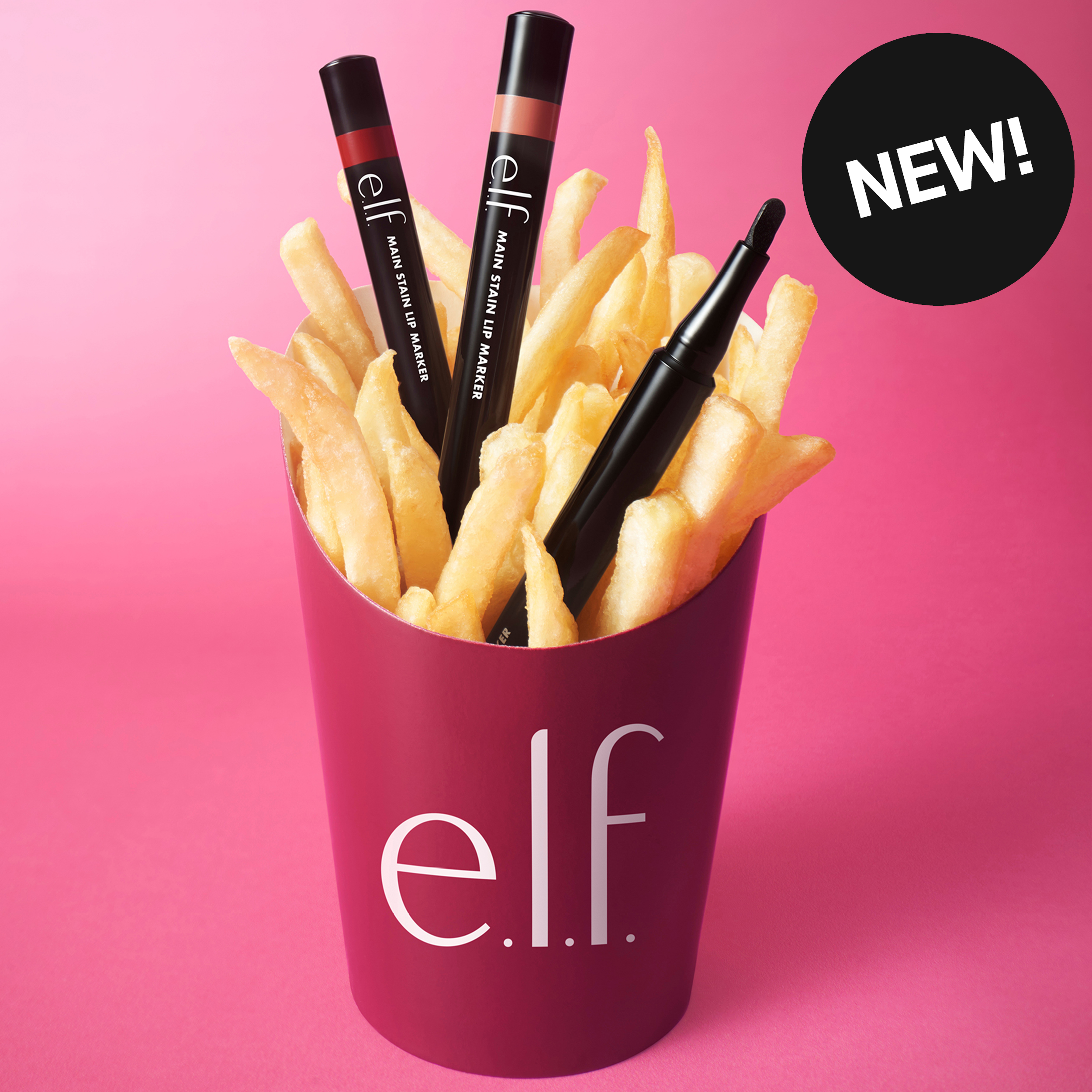 e.l.f. Main Stain Lip Marker-leppefarger plassert blant pommes frites mot rosa bakgrunn. Bildet inneholder teksten «NEW!».