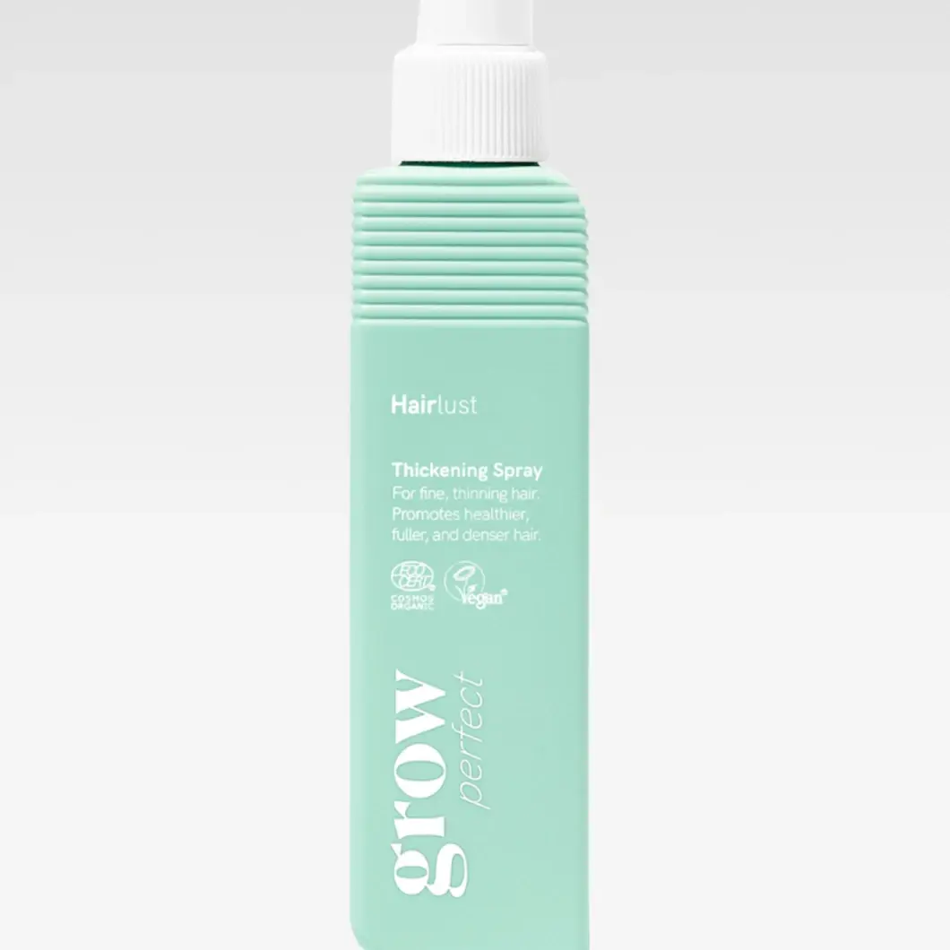 Grow Perfect Thickening Spray on tuuheuttava hiussuihke mintunvihreässä suihkepullossa. Pakkauksessa näkyvät tekstit "Hairlust", "Thickening Spray", "For fine, thinning hair. Promotes healthier, fuller, and denser hair.", "COSMOS ORGANIC", "Vegan" ja "grow perfect".