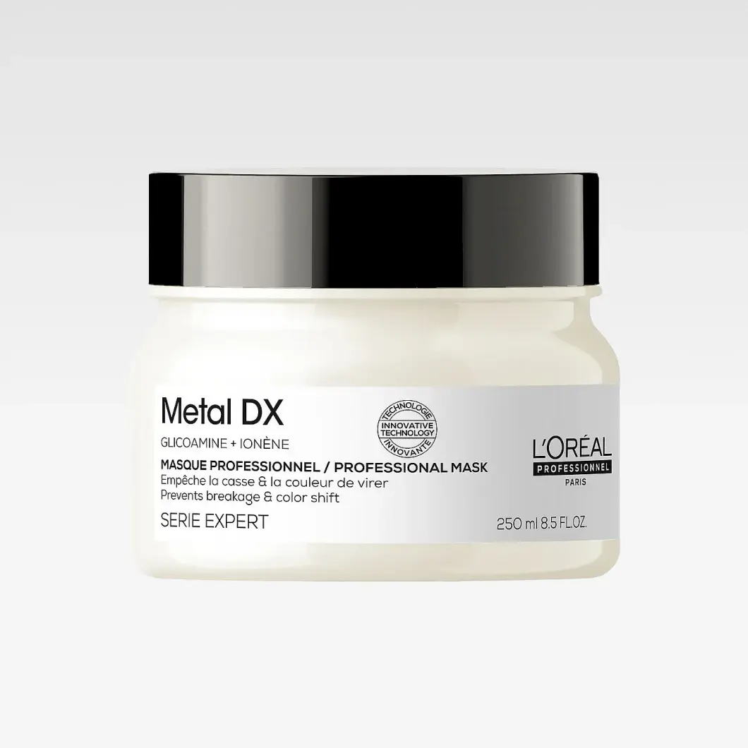 L'Oréal Professionnel Serie Expert Metal DX Professional Mask är en hårmask i en vit burk med svart lock. På förpackningen syns texterna "Metal DX", "GLICOAMINE + IONÈNE", "MASQUE PROFESSIONNEL / PROFESSIONAL MASK", "Prevents breakage & color shift", "SERIE EXPERT", "L'ORÉAL PROFESSIONNEL PARIS" och "250 ml".