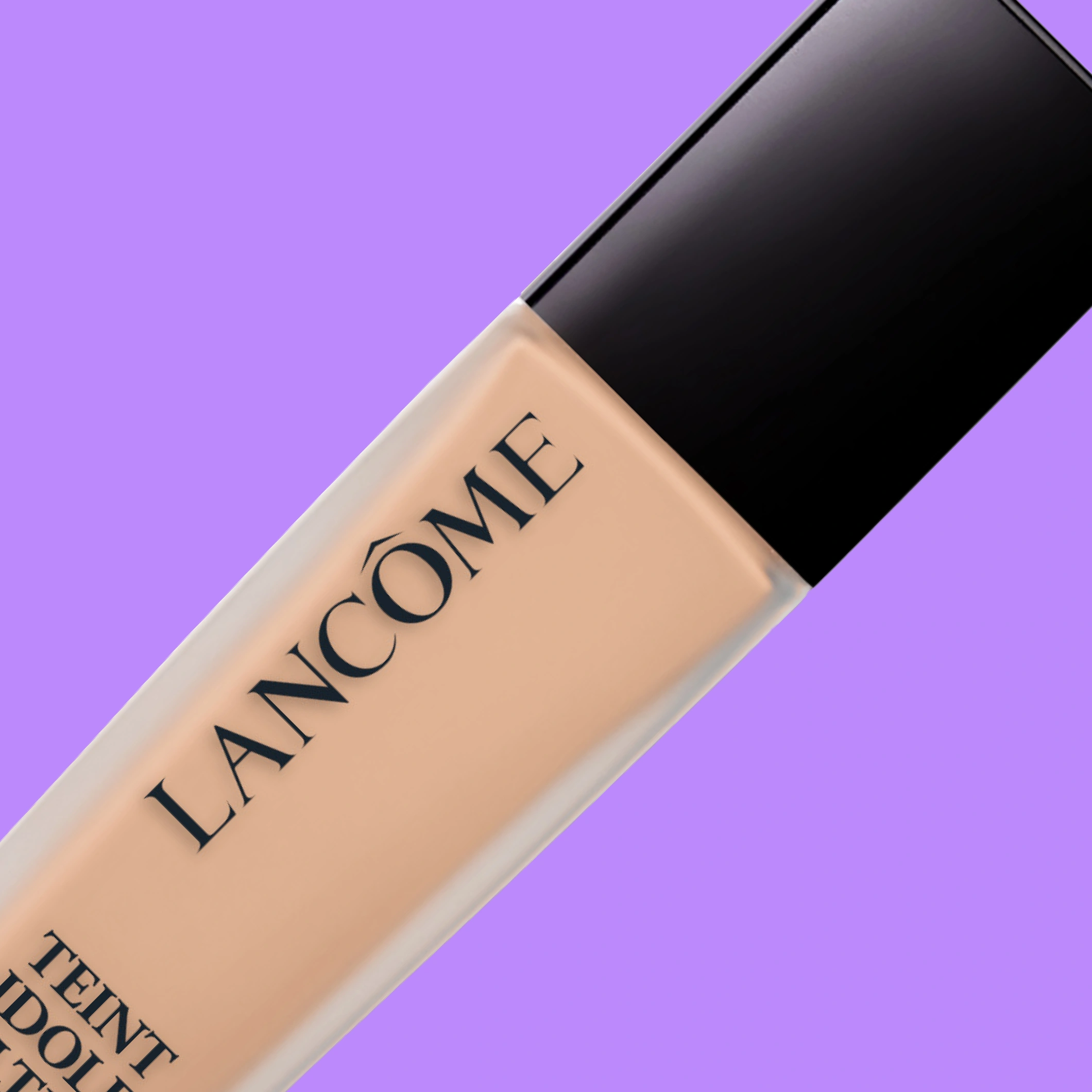 Lähikuva Lancôme Teint Idole Ultra Wear -meikkivoiteesta lasipullossa, jossa on musta korkki, vinosti violettia taustaa vasten.