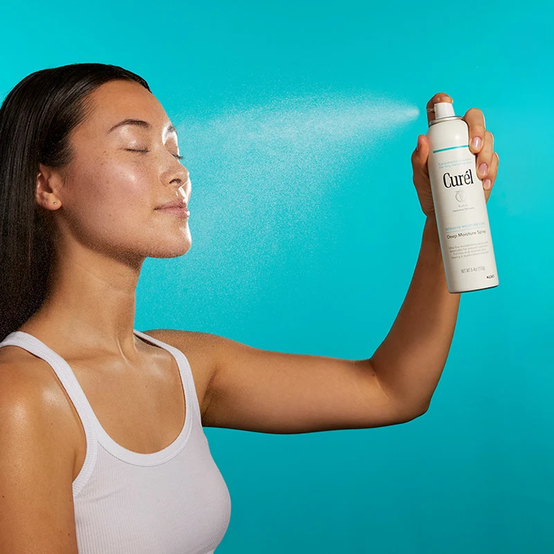 Kvinne sprayer Curél-fuktighetsspray i ansiktet.