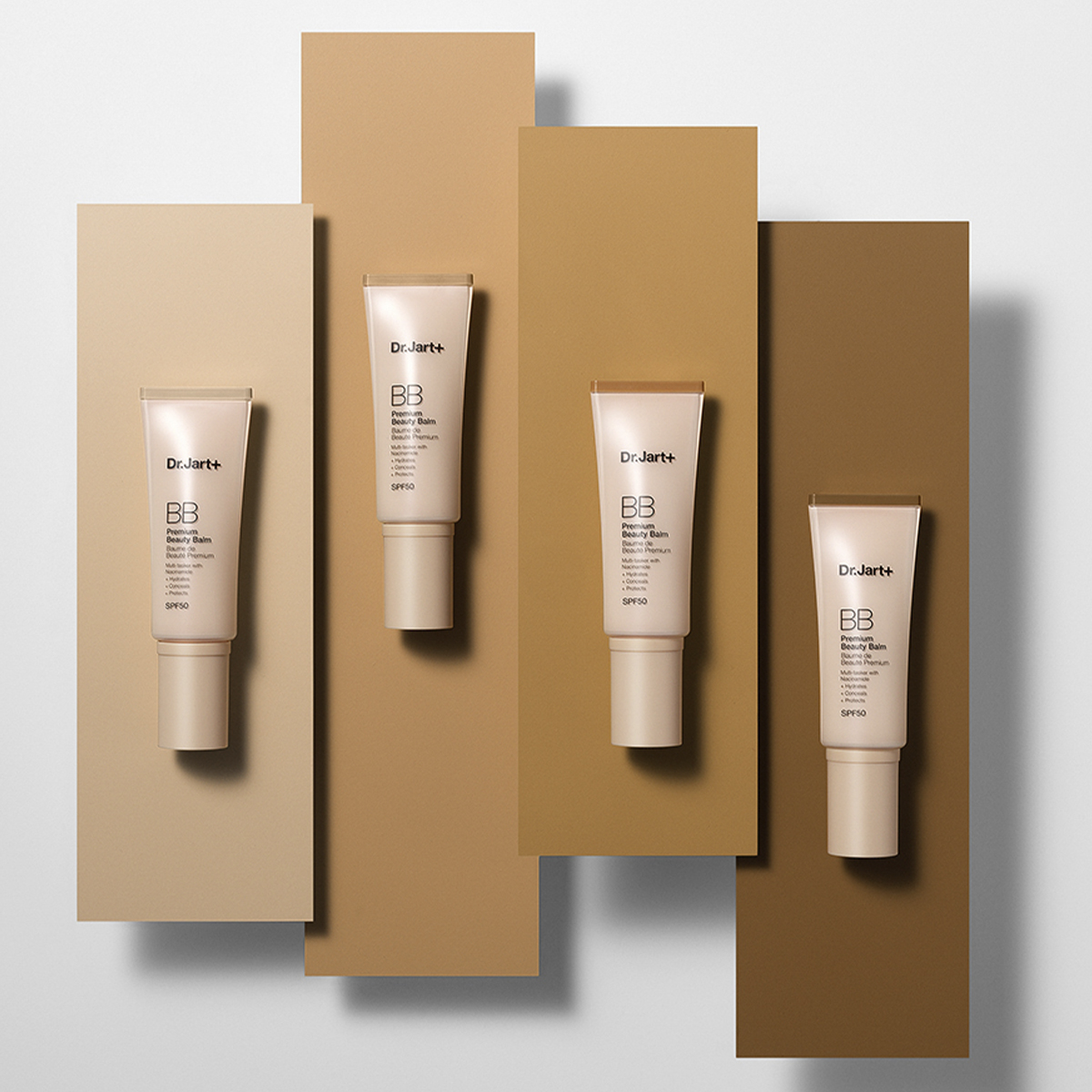 Neljä tuubia Dr.Jart+ BB Beauty Balm SPF 50 -voidetta, jotka on sijoitettu erilaisille beige- ja ruskeansävyisille taustoille.