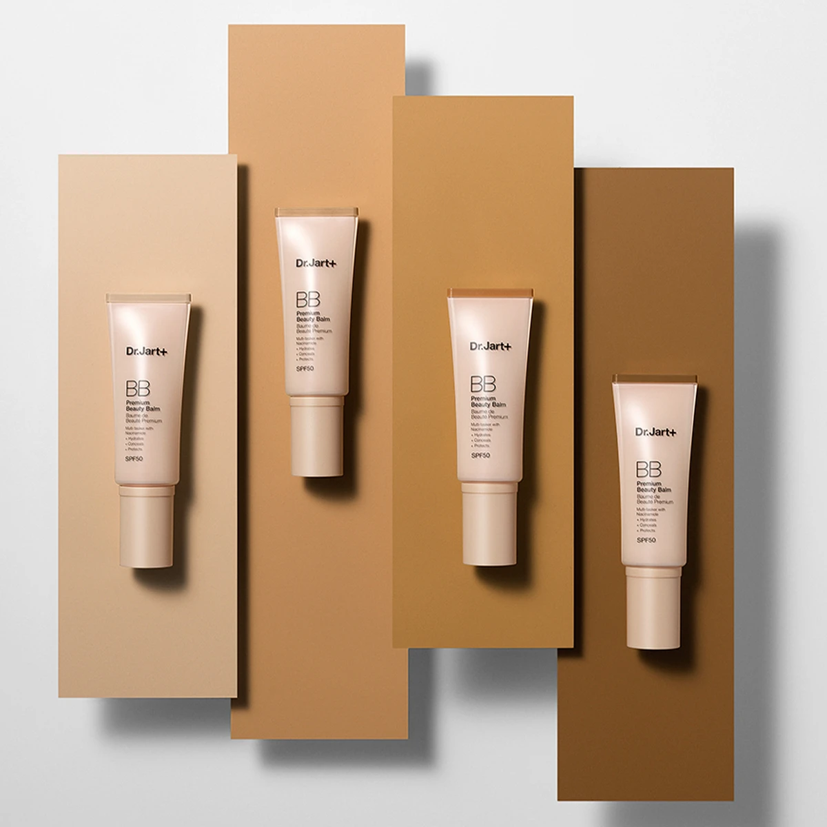 Neljä tuubia Dr.Jart+ BB Beauty Balm SPF 50 -voidetta, jotka on sijoitettu erilaisille beige- ja ruskeansävyisille taustoille.