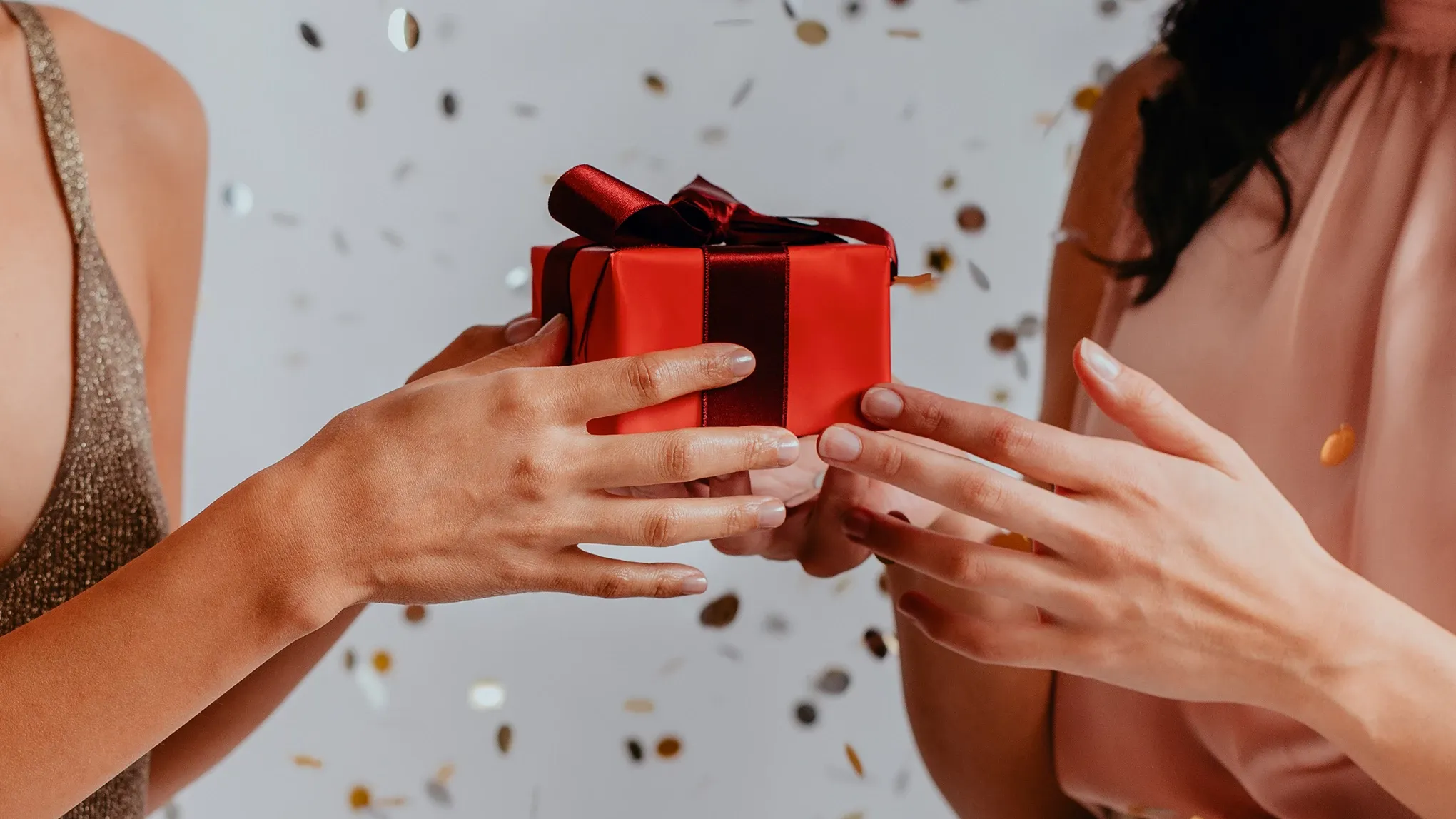 To personer holder en rød gaveeske med et rødt bånd.