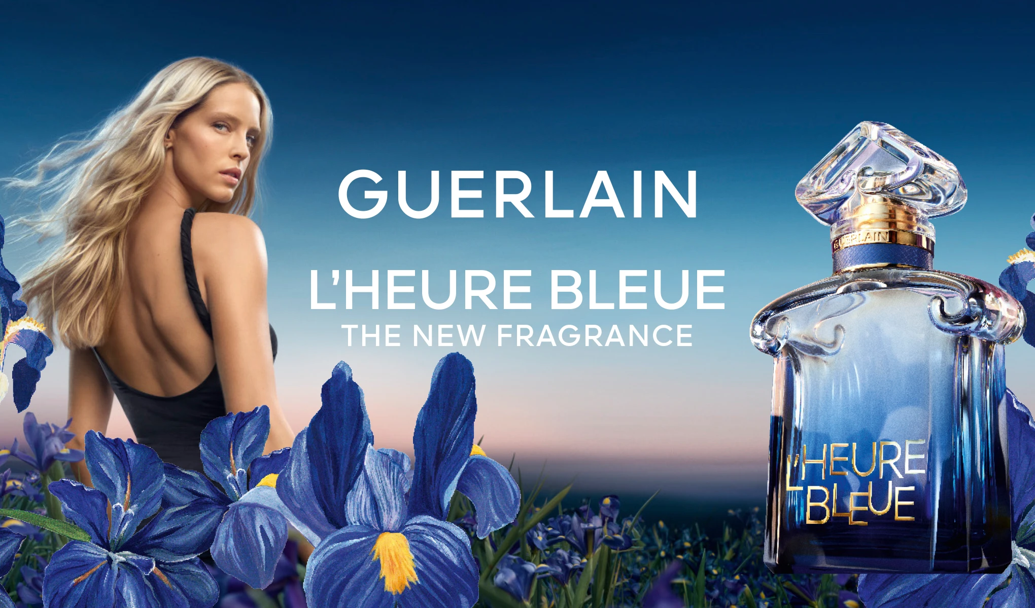 Kvinna bland blå irisar och Guerlain L’Heure Bleue-parfymflaska. Text: ”Guerlain L’Heure Bleue. The new fragrance.”