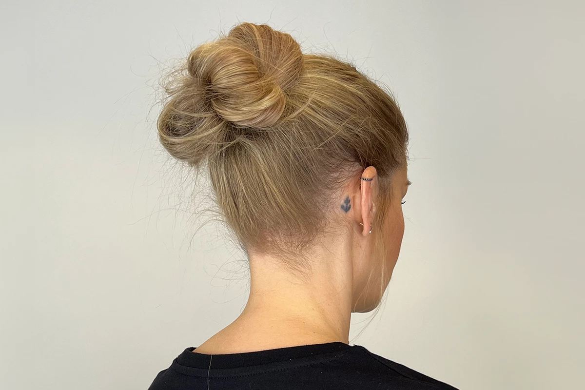 En person med blont hår uppsatt i en knut, fotograferad bakifrån.